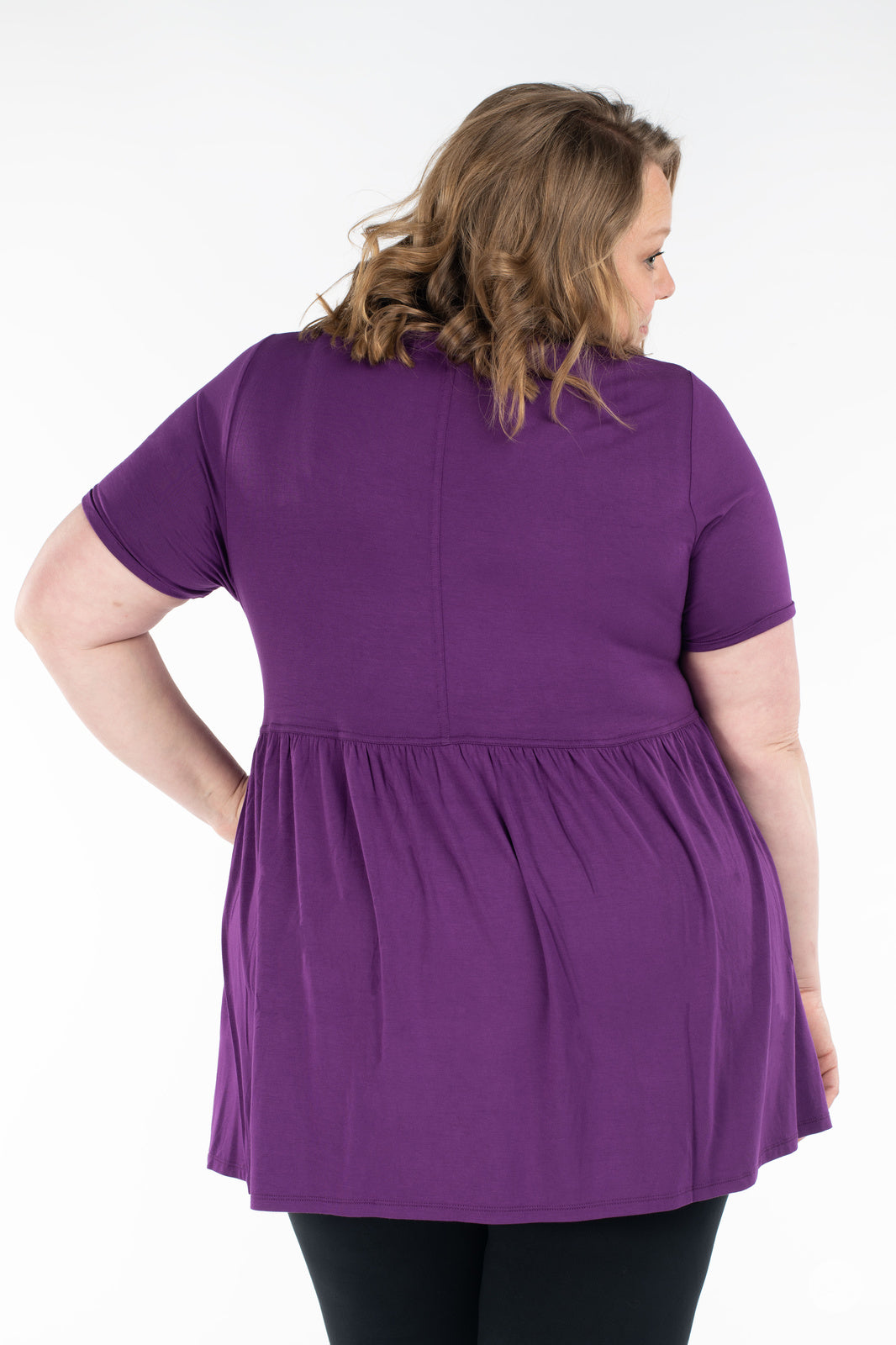 Plus-size woman showing back view wearing purple Babydoll Tee by SweetLegs Canada with short sleeves and babydoll shape