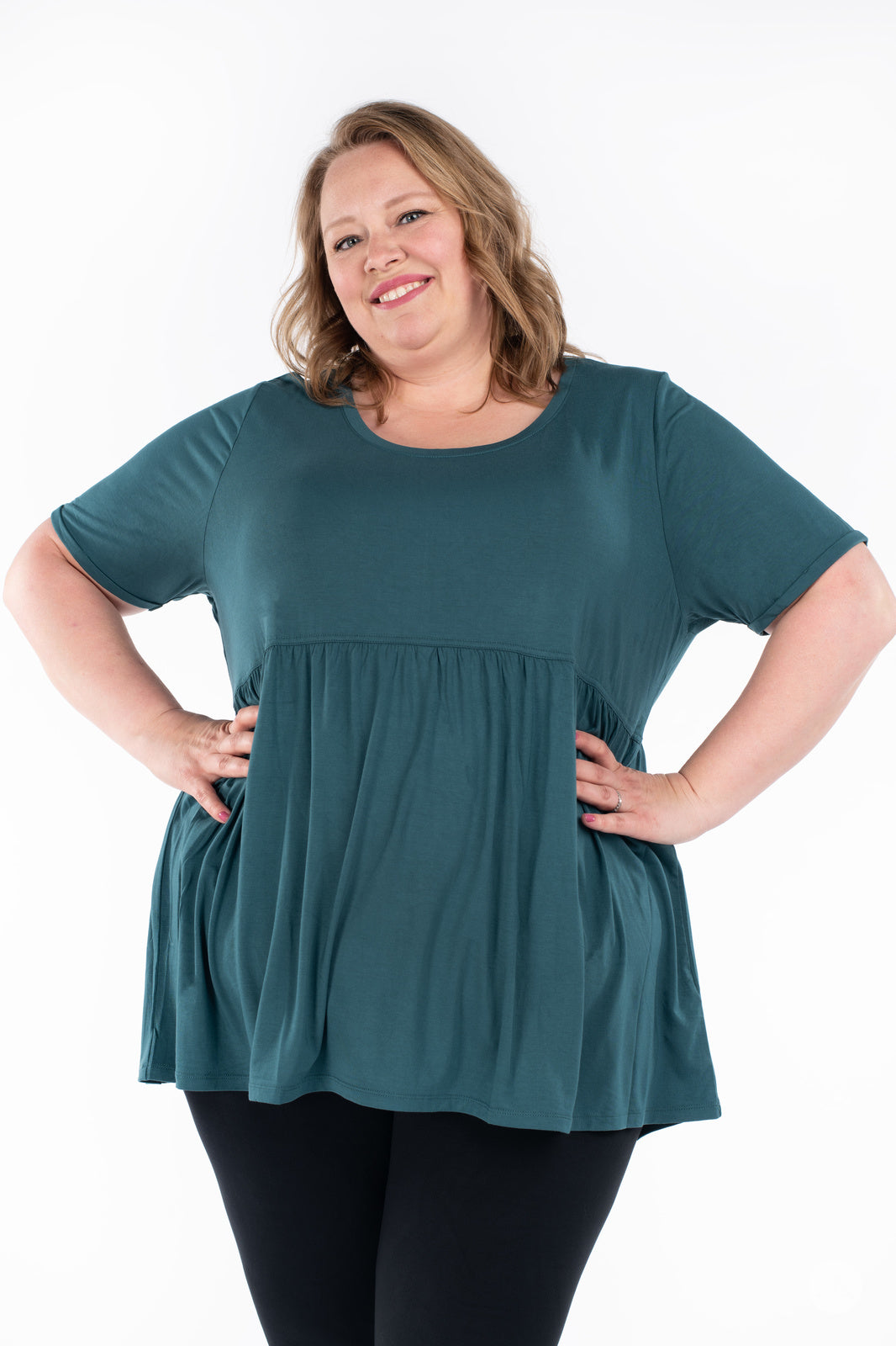 Plus-size woman smiling wearing teal Babydoll Tee by SweetLegs Canada with short sleeves and relaxed fit front view