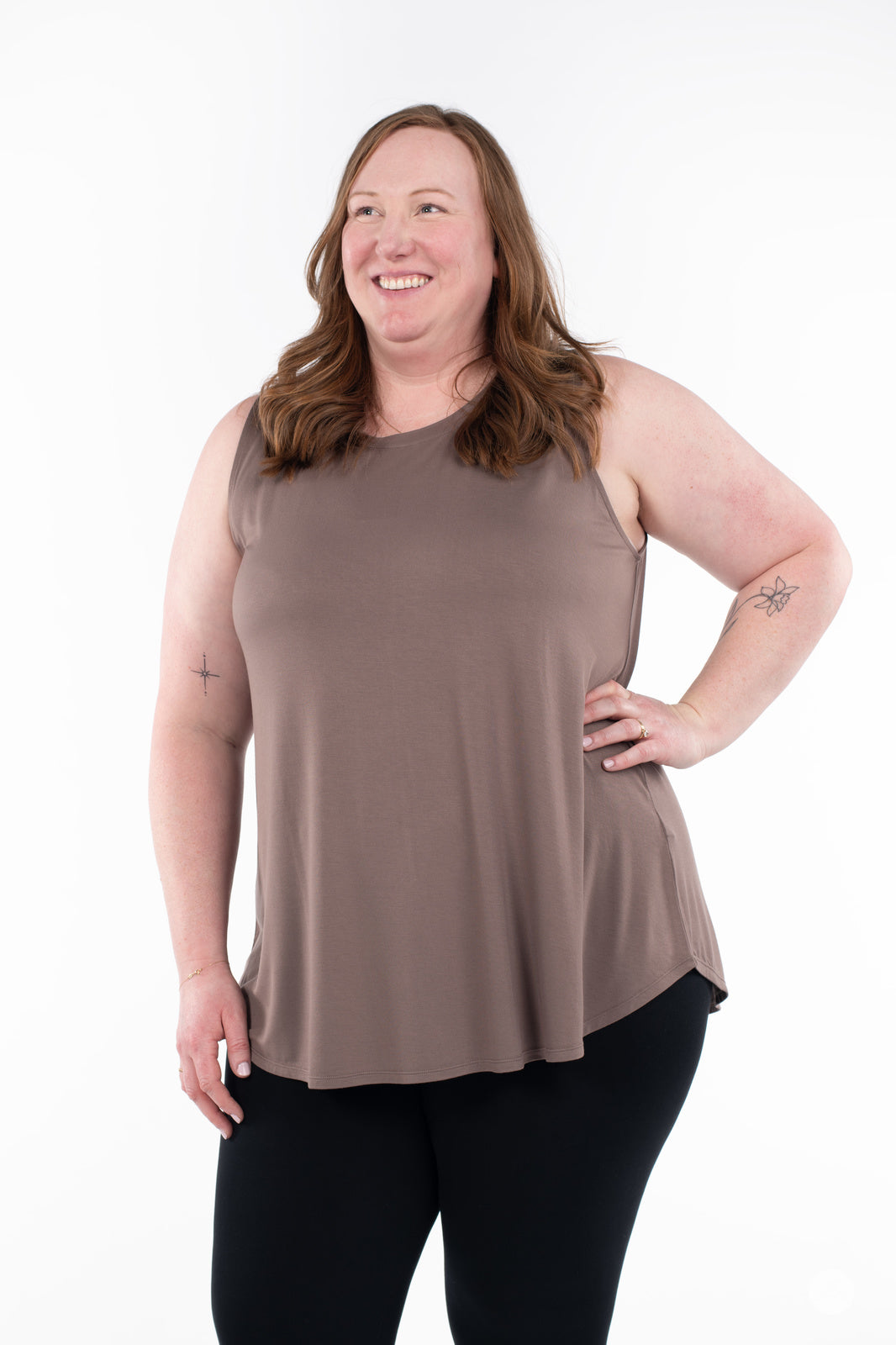 Plus-size woman smiling wearing SweetTops High Neck Swing Tank in brown paired with black leggings on white background