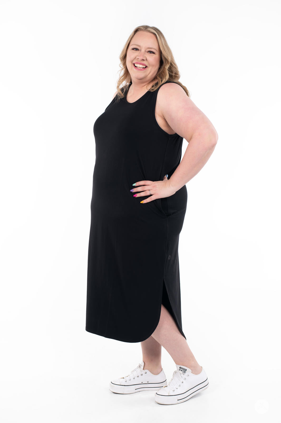 Plus-size woman wearing black Sleeveless Tank Dress by SweetTops smiling and posing with hand on hip on white background