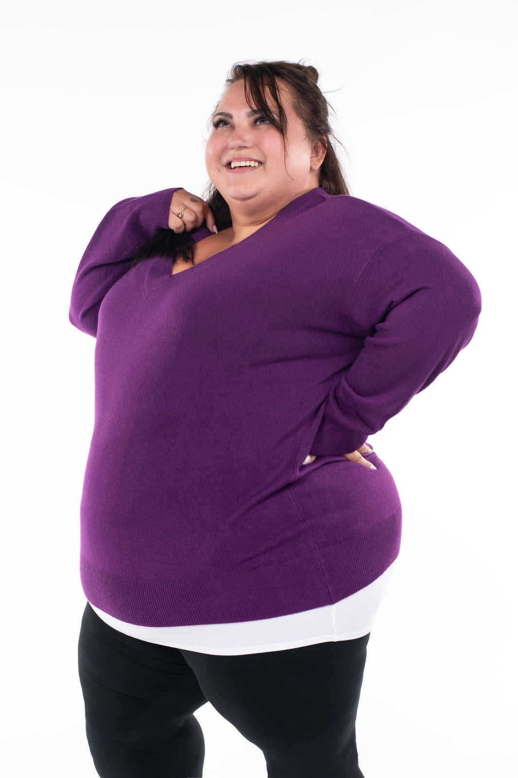 Plus size model smiling in SweetTops Soft Knit V-Neck Sweater in vibrant purple with relaxed fit and ribbed hem details
