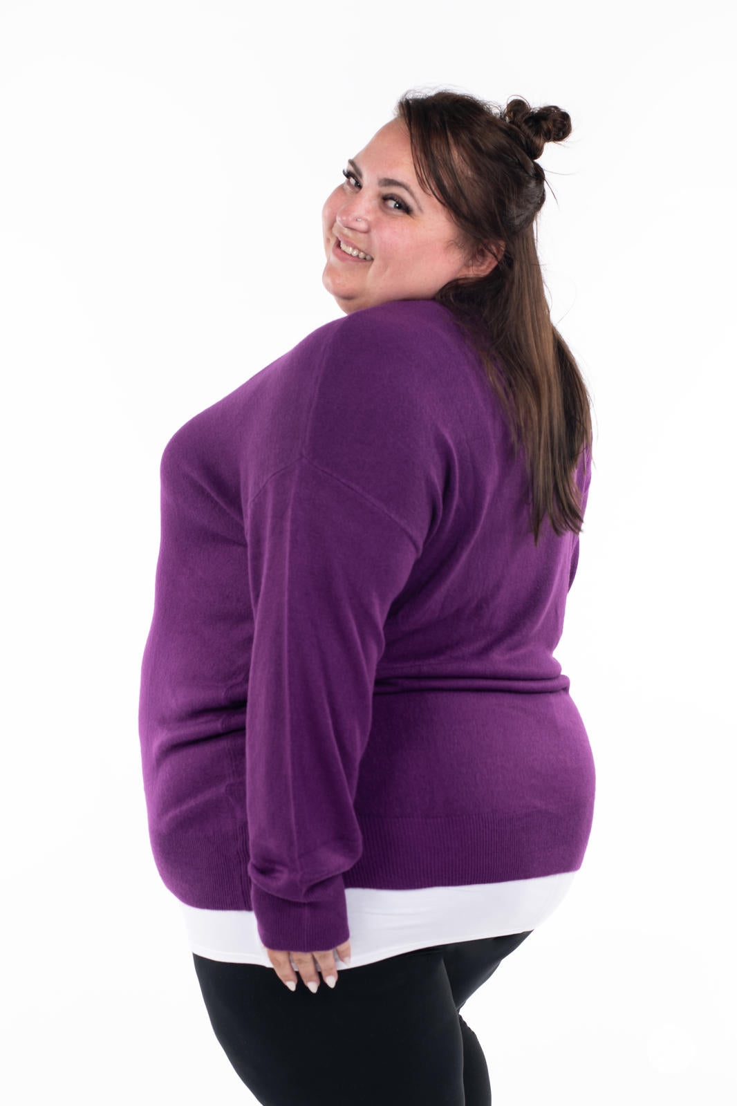 Plus size model smiling wearing SweetTops Soft Knit V-Neck Sweater in vibrant purple with relaxed fit and ribbed hem