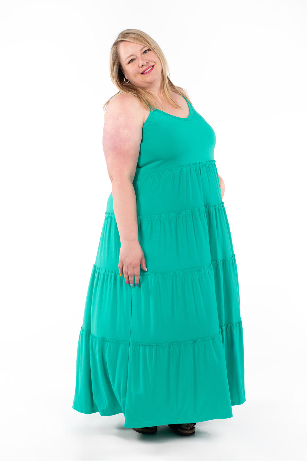 Plus-size model wearing SweetTops The Summer Tiered Dress in green with tiered skirt and adjustable straps smiling at camera