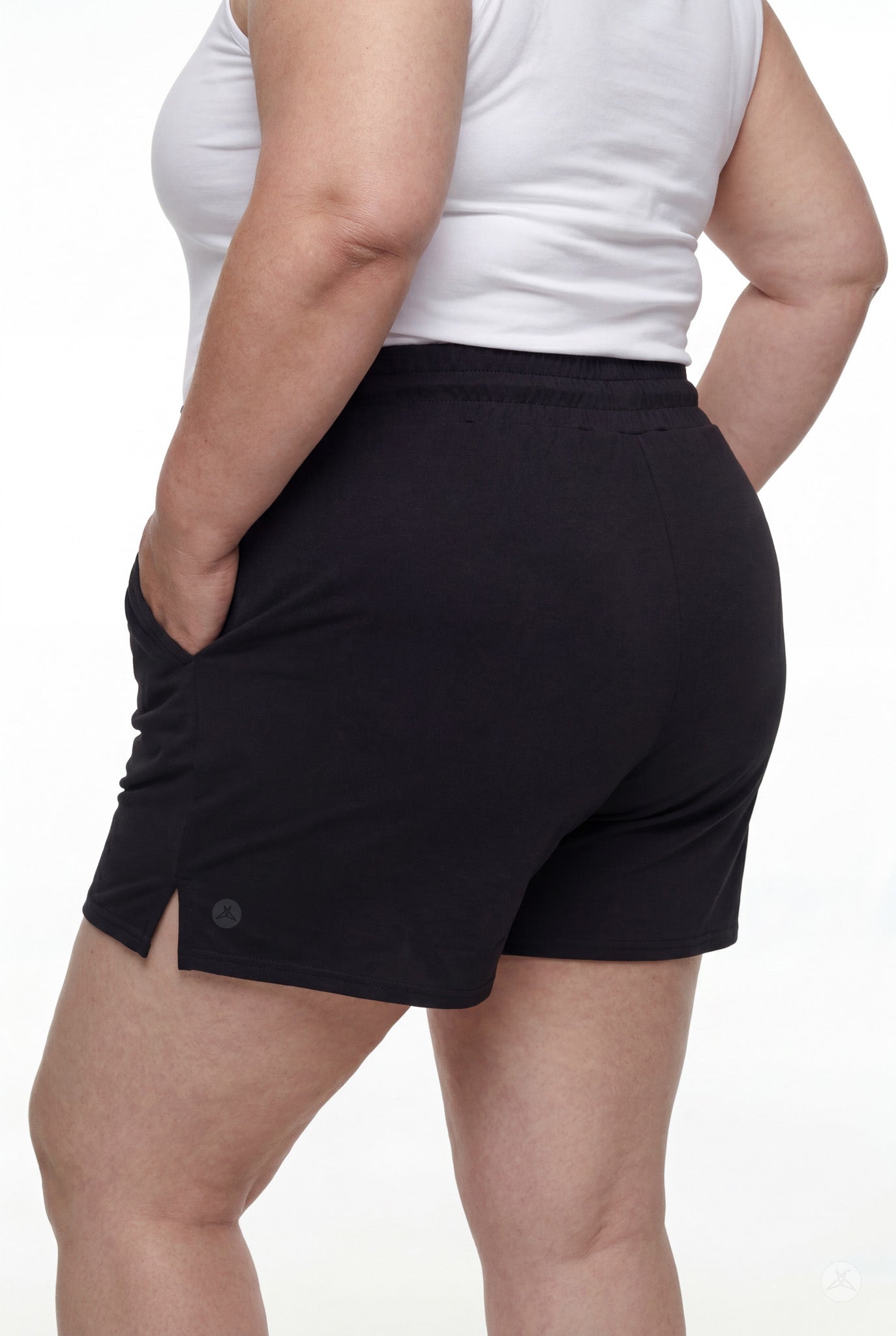 Rear angle of person wearing black Lounge Shorts by SweetLegs with side slits and elastic waistband with hands in pockets