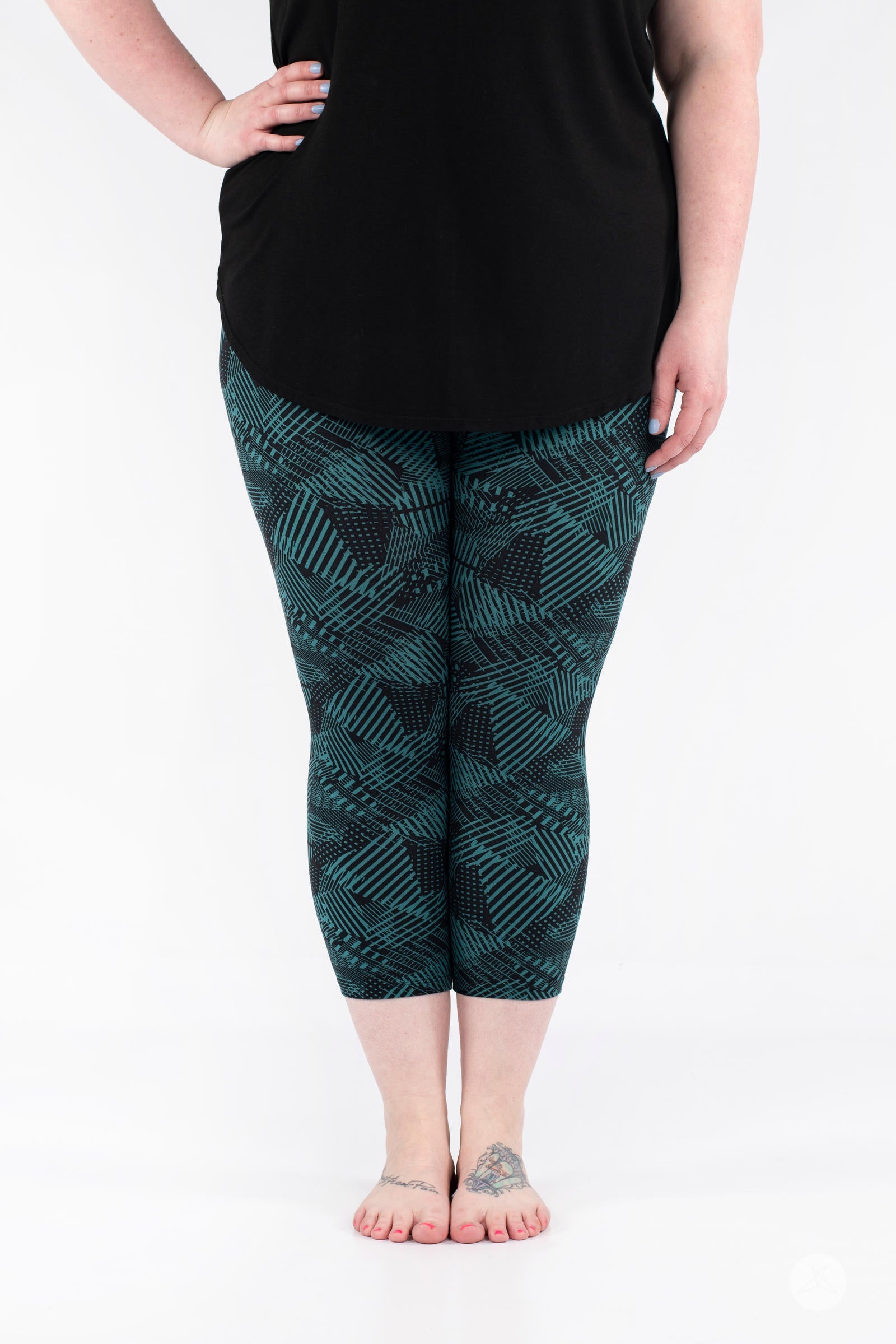 Front view of SweetLegs Geometric Glam Crops featuring teal and black abstract geometric patterned cropped leggings
