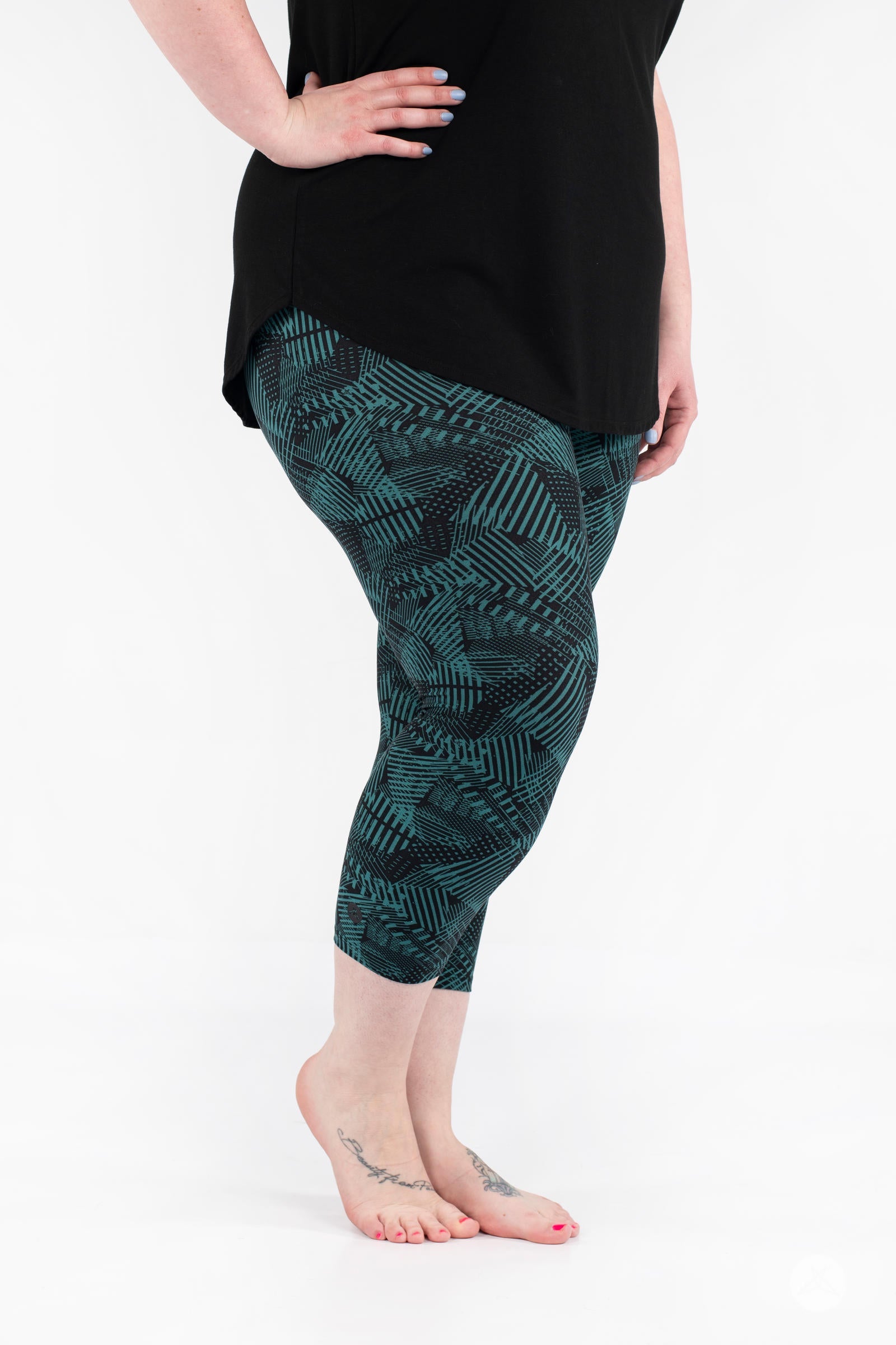 Side view of plus size model wearing SweetLegs Geometric Glam Crops with teal and black geometric cropped leggings
