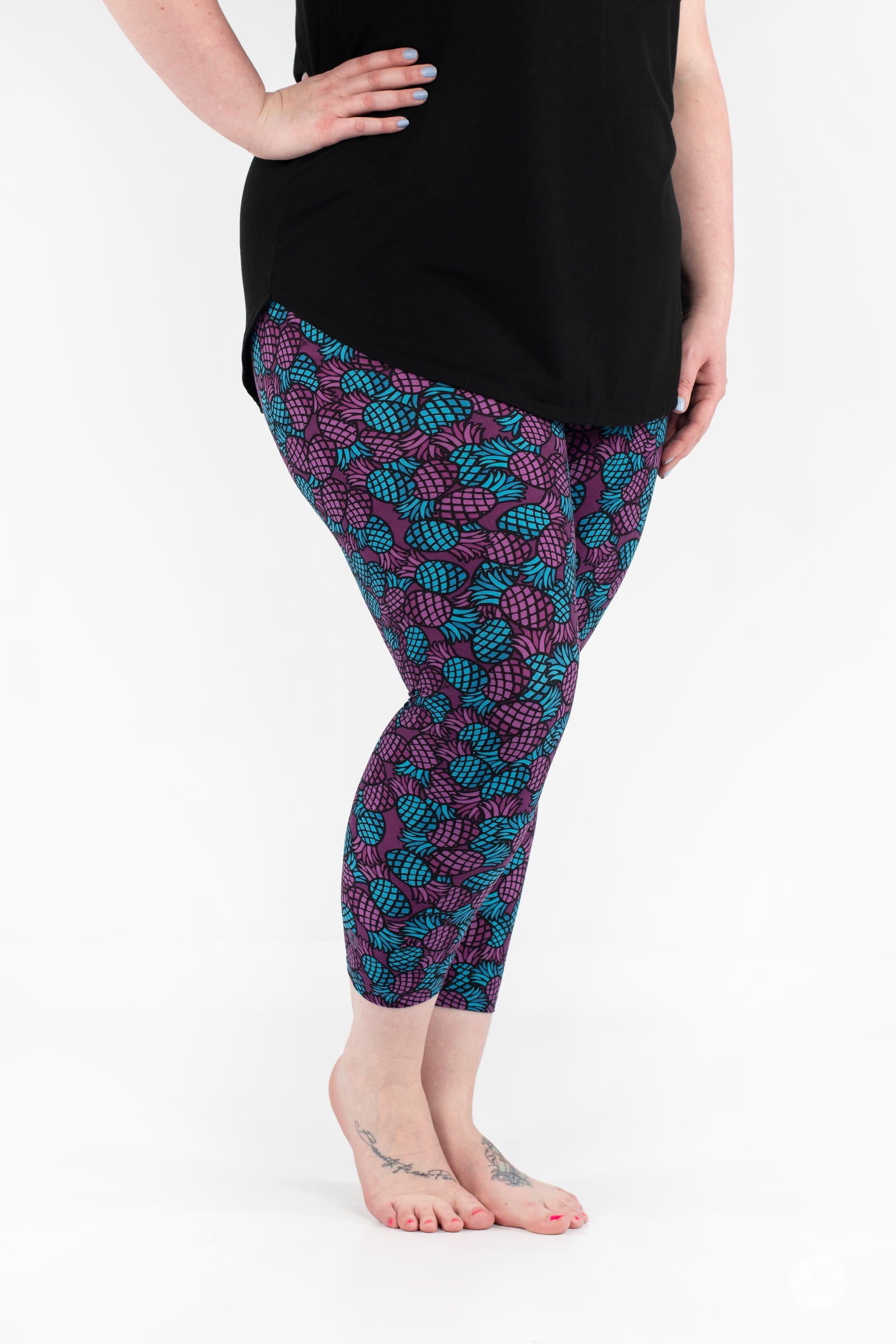 Woman wearing SweetLegs Razzle Dazzle Crops with purple and teal pineapple pattern in side pose