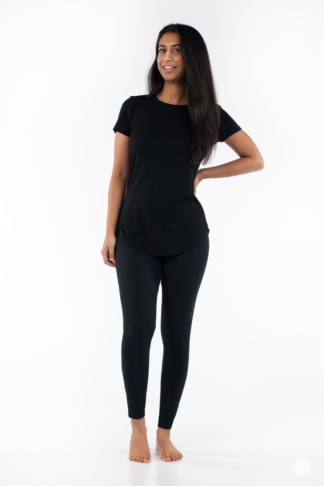 Woman smiling wearing SweetLegs Black Licorice leggings and black short sleeve top barefoot on white background
