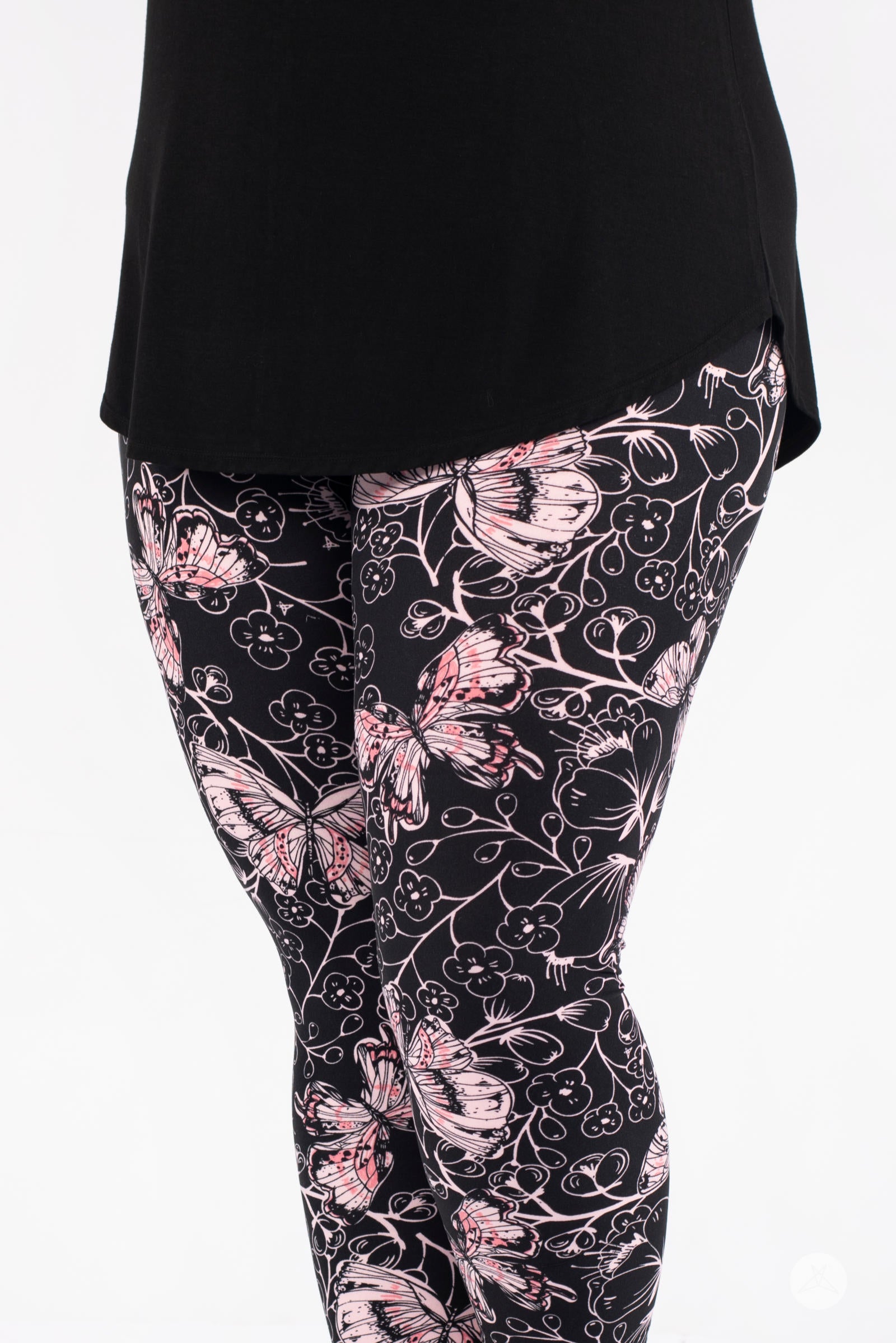 Close-up of SweetLegs Butterfly Bliss 2.0 Crops with delicate pink butterfly and floral print on black fabric under tunic top