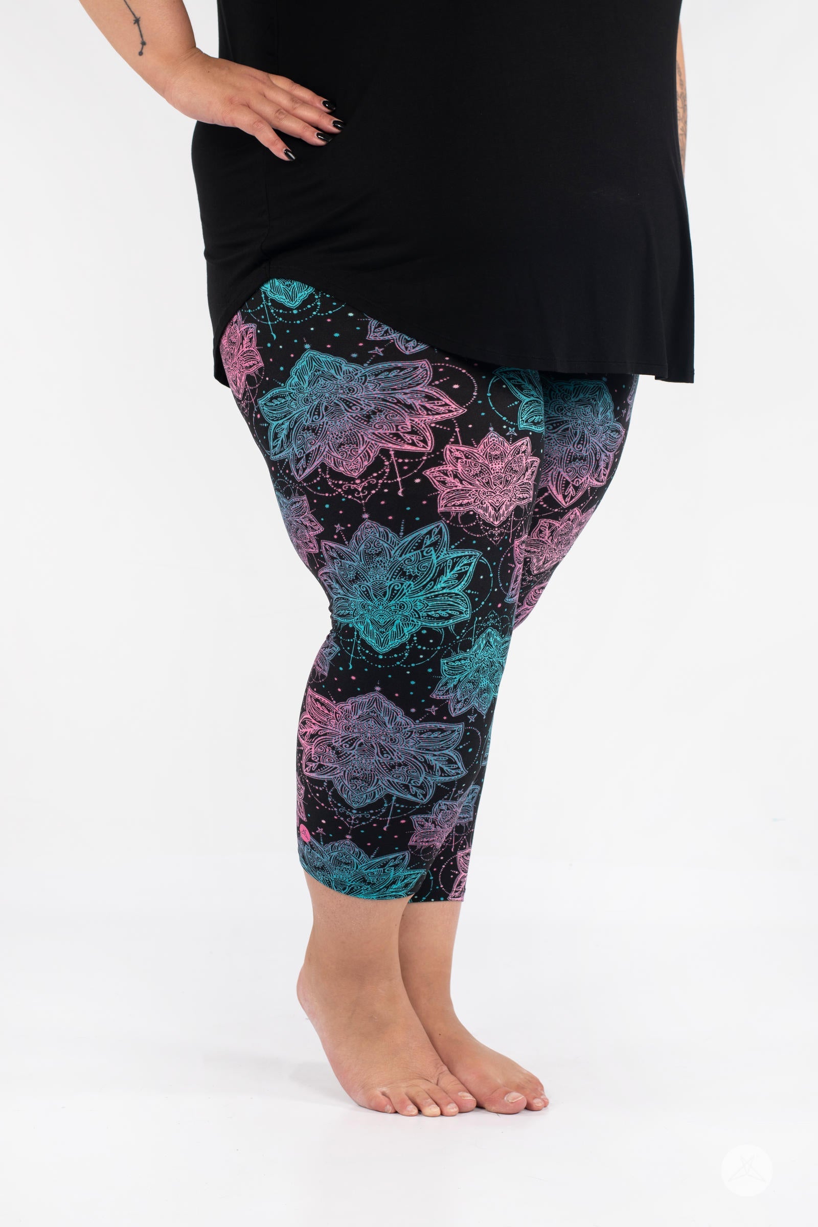 Side view of plus-size model wearing SweetLegs Everafter Crops with pink and teal floral geometric pattern on black background