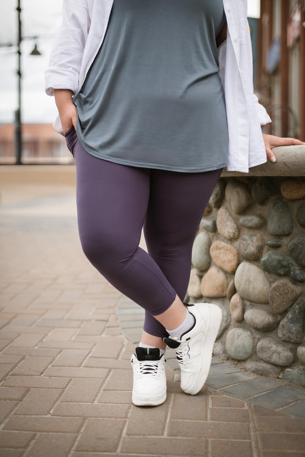 Plus-size model wearing plum SweetLegs High-Waist Pocket Crops standing outdoors with hands in pockets and white sneakers