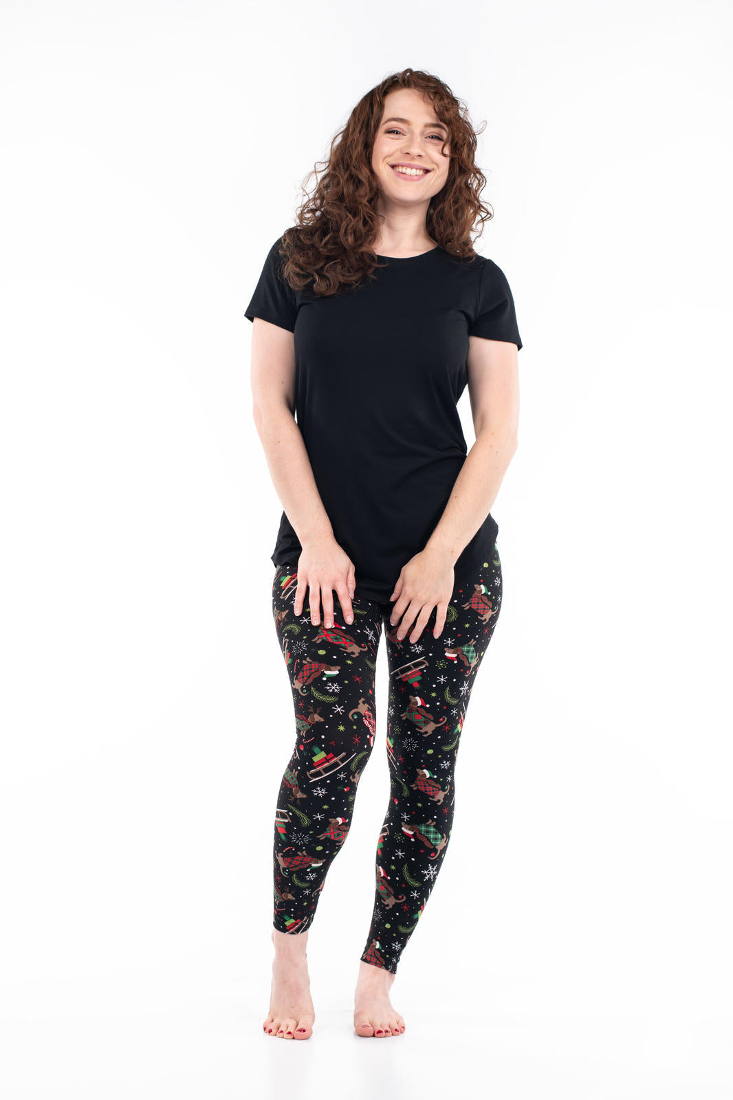Woman wearing SweetLegs Happy Pawlidays leggings with festive Dachshunds, gifts, and snowflakes on black background