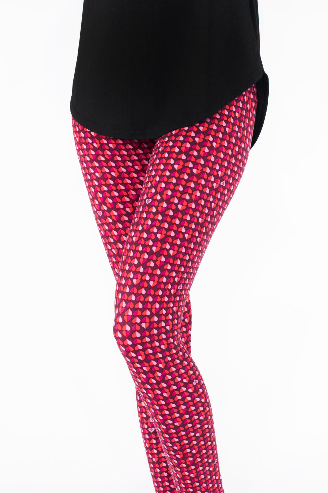 Close-up of SweetLegs Lovesick leggings featuring repeating pink and purple duo-colored hearts worn with black top
