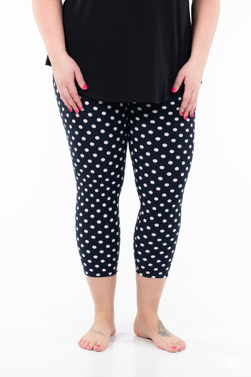 Front view of SweetLegs Get Spotted Crops navy leggings with white polka dots worn with black top on white background