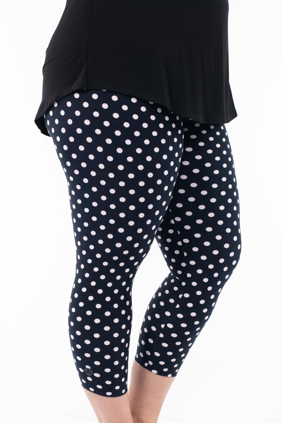 Side view of SweetLegs Get Spotted Crops navy leggings with white polka dots paired with black top on white background