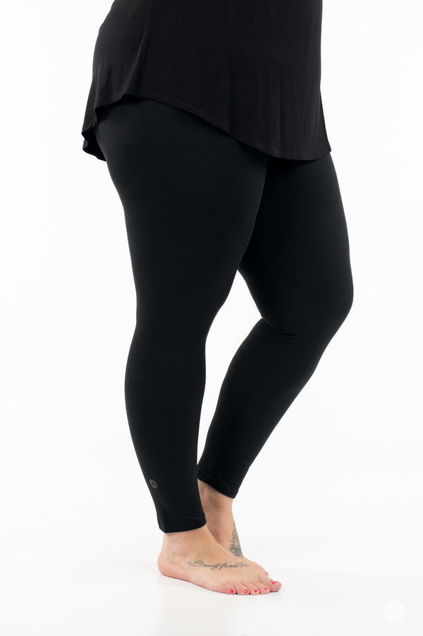 Side view of adult wearing SweetLegs Black Licorice leggings with black top on white background