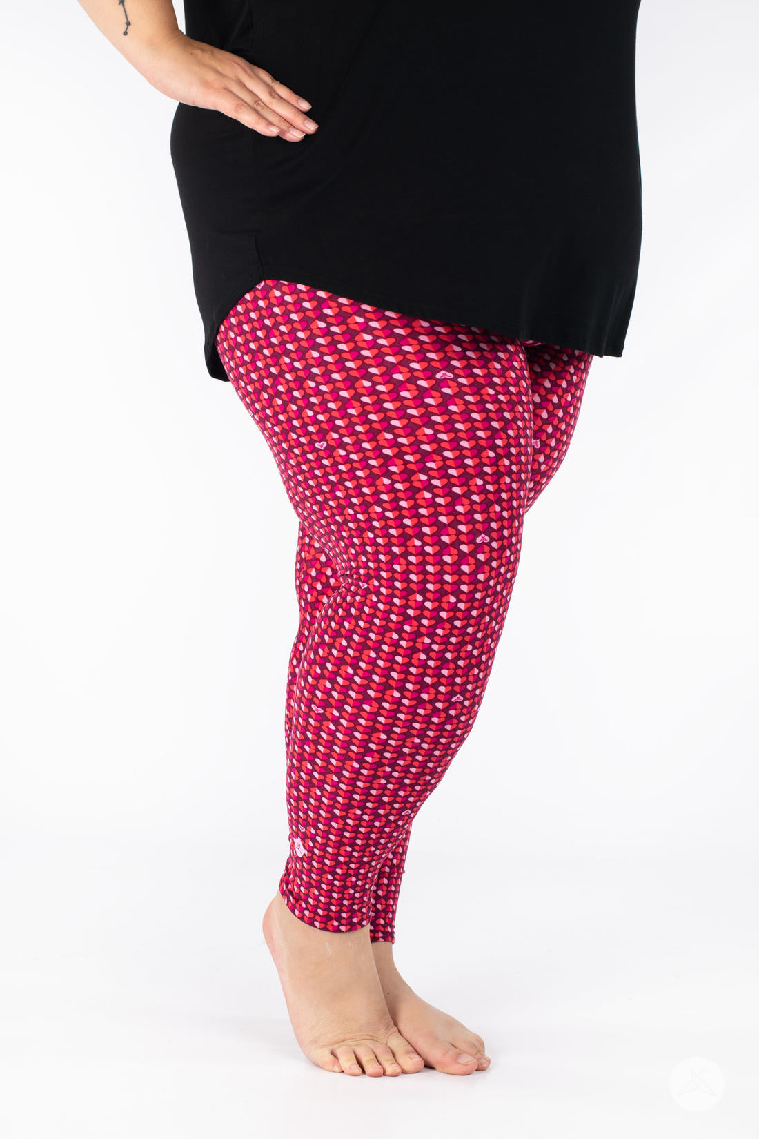 Side profile of SweetLegs Lovesick leggings showcasing repeating bold pink and purple heart pattern worn barefoot