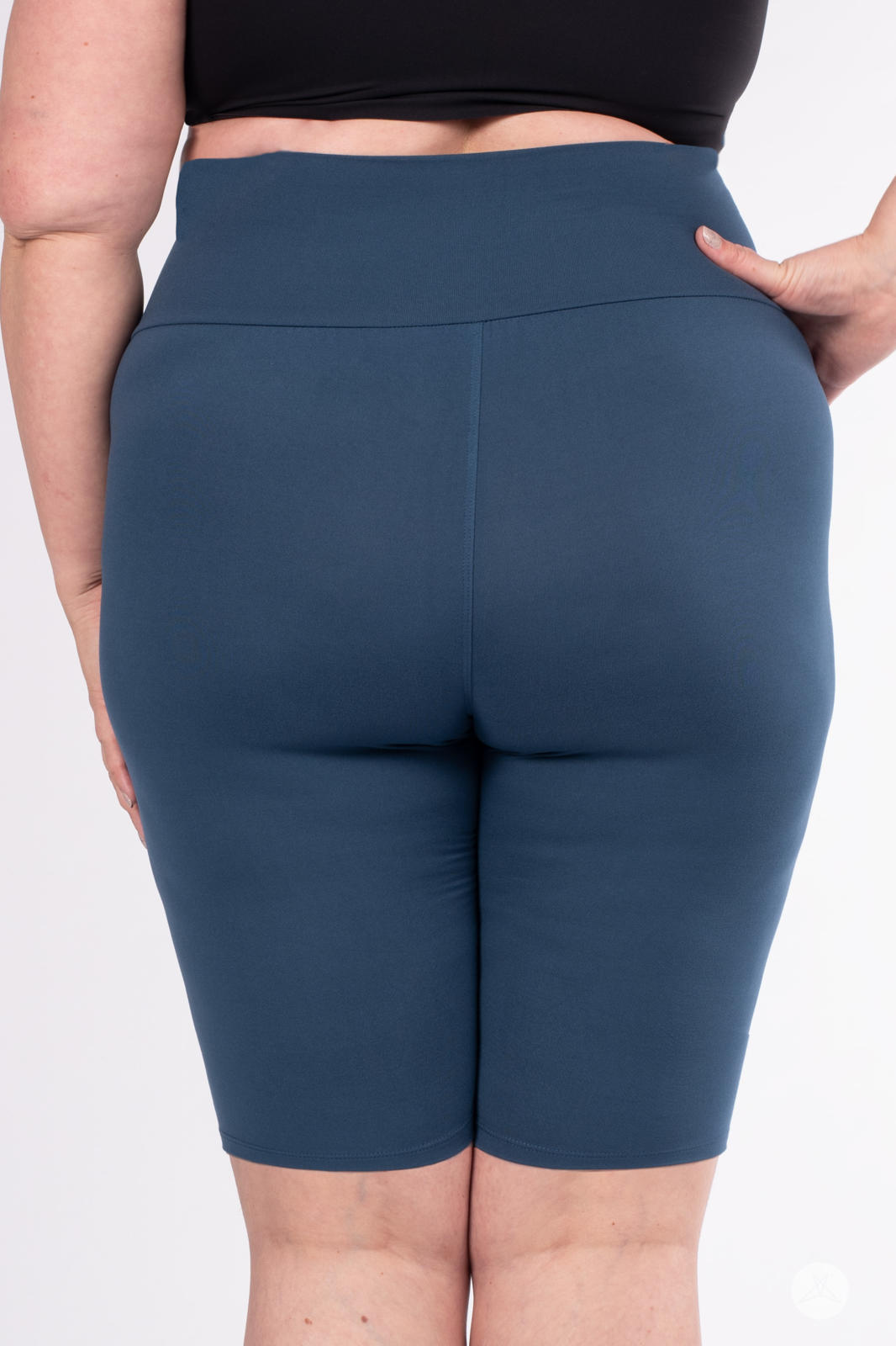 Rear view of plus-size model wearing SweetLegs Solid High-Waisted Biker Shorts in rich blue with wide waistband