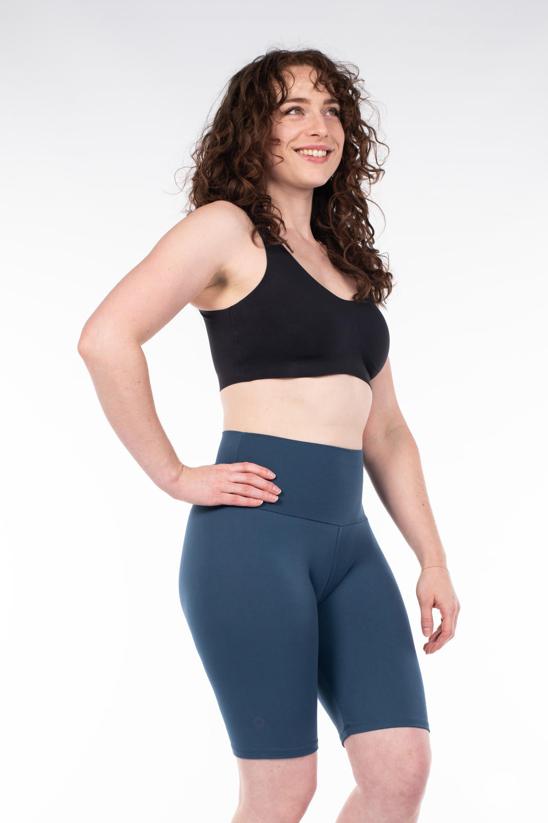 Smiling woman modeling SweetLegs Solid High-Waisted Biker Shorts in dark blue with a comfortable high-rise fit