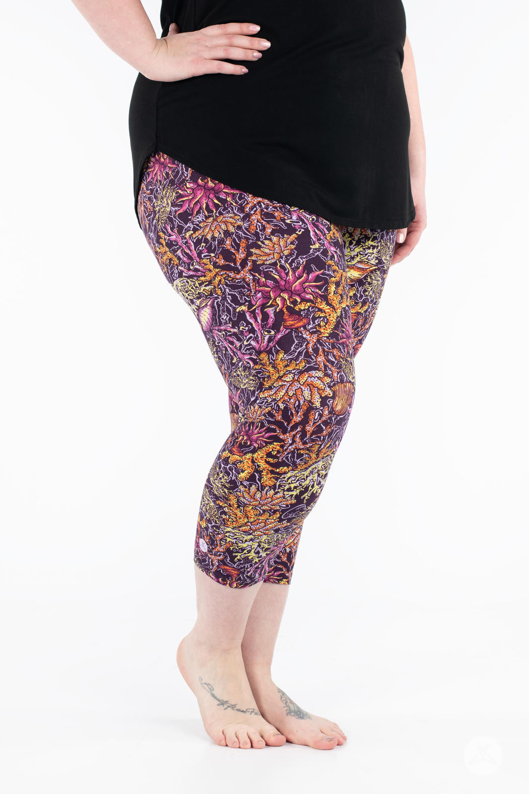 Close-up front view of SweetLegs Coral Cove Crops with vibrant sea life design cropped above the ankle on a plus size model