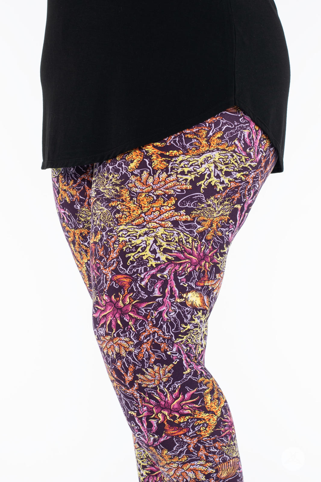 Close-up of SweetLegs Coral Cove Crops showing detailed vibrant coral reef pattern in warm purple, orange, and pink tones