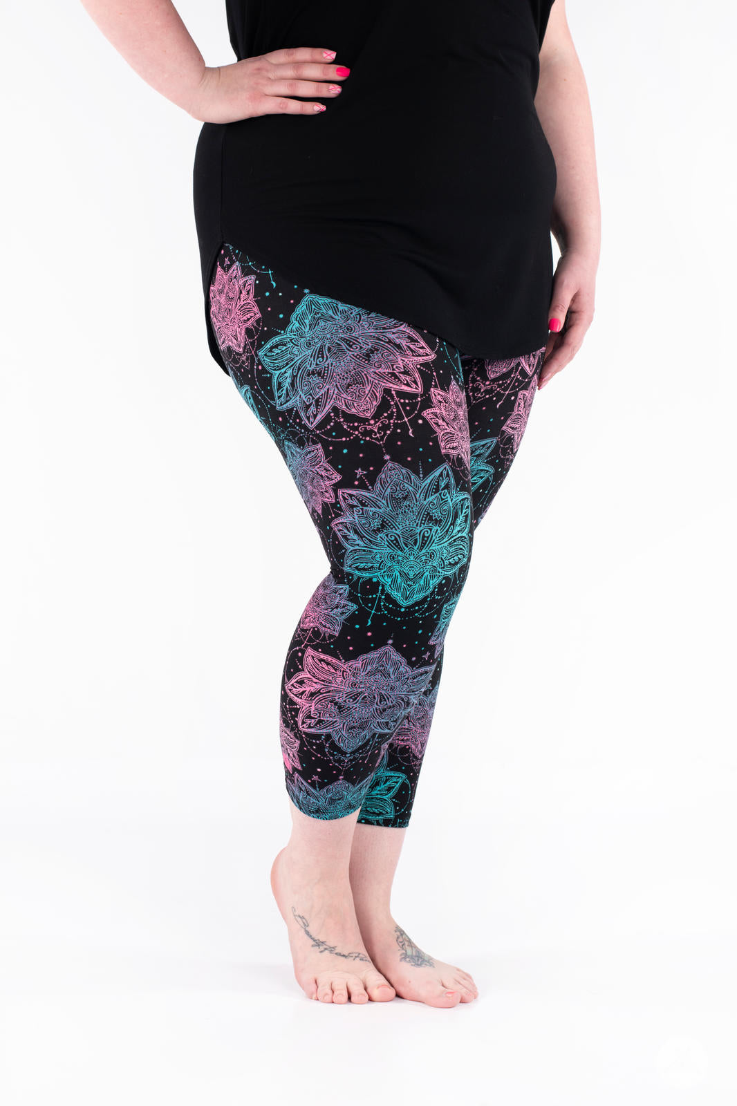 Side view of plus-size model wearing SweetLegs Everafter Crops with pink and teal large floral pattern on black background