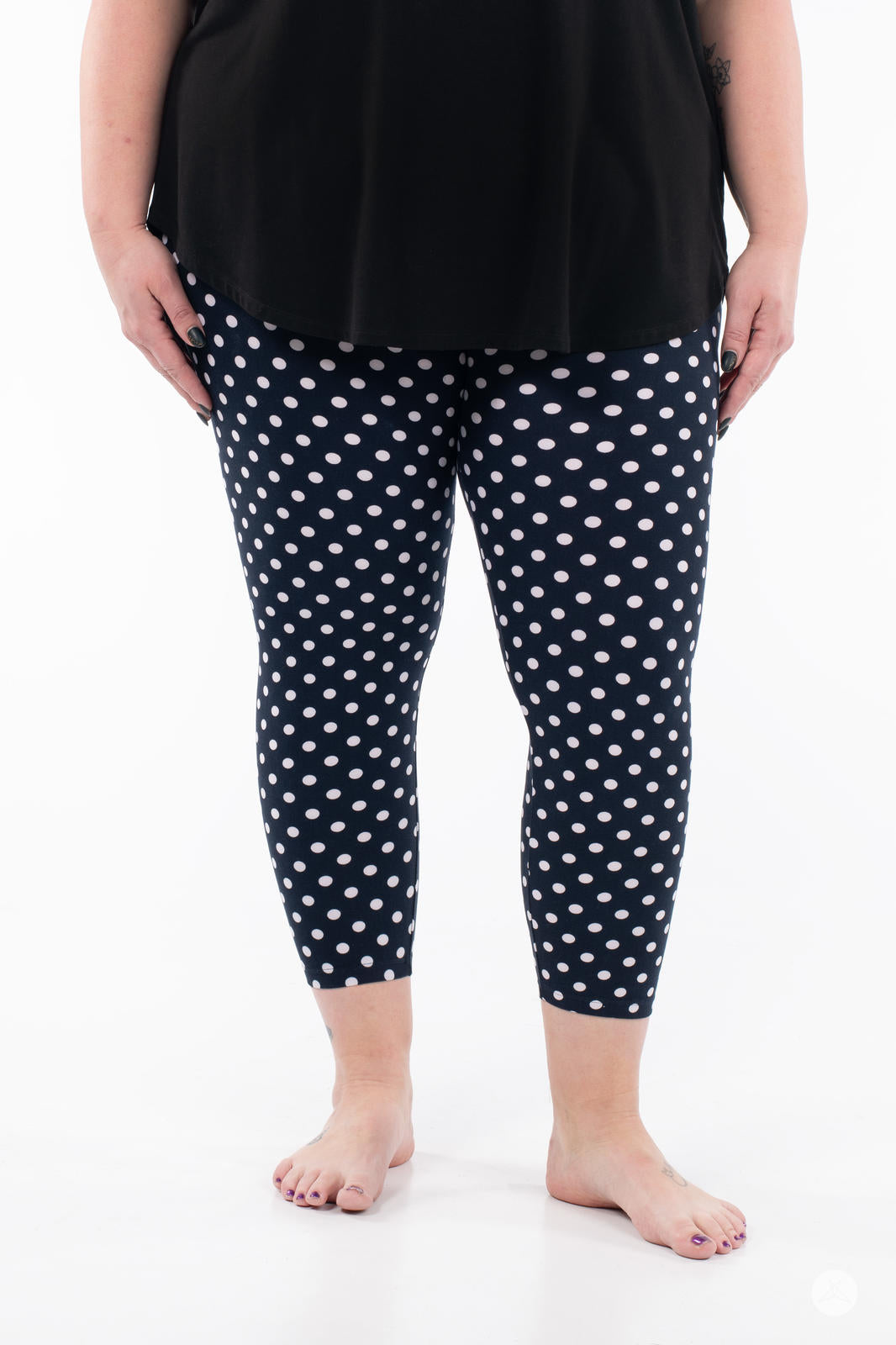 Front view of SweetLegs Get Spotted Crops navy leggings with white polka dots worn with black top on white background