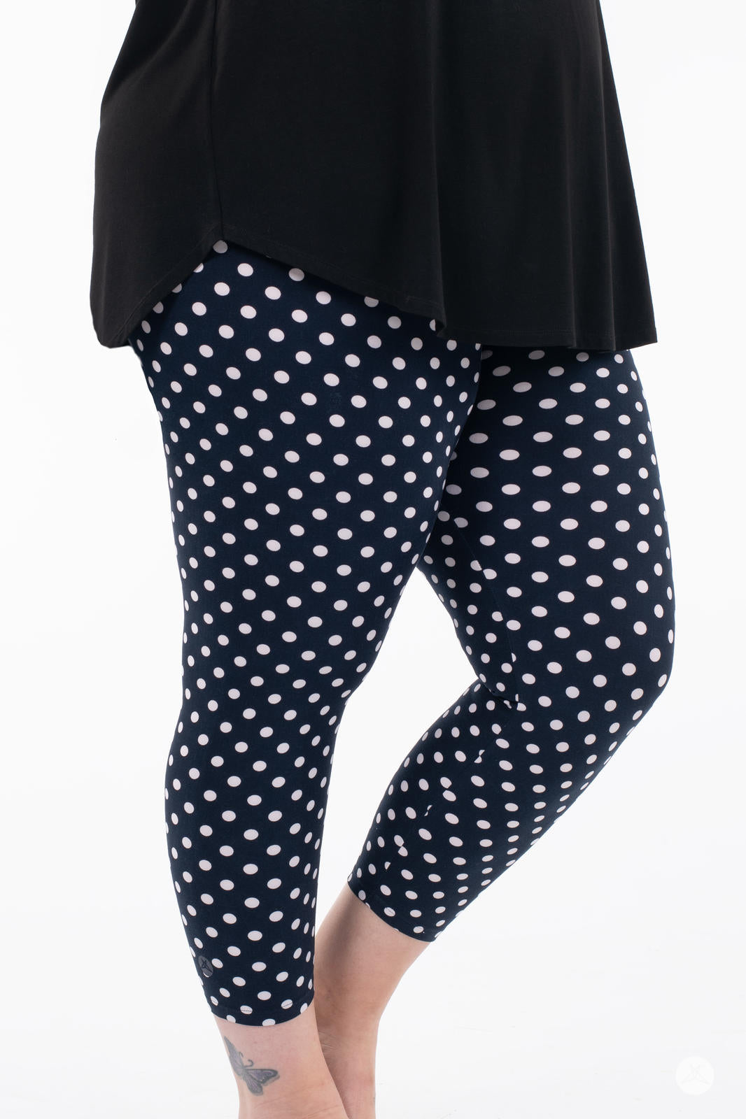 Close-up side view of SweetLegs Get Spotted Crops navy leggings with white polka dots worn with a black top