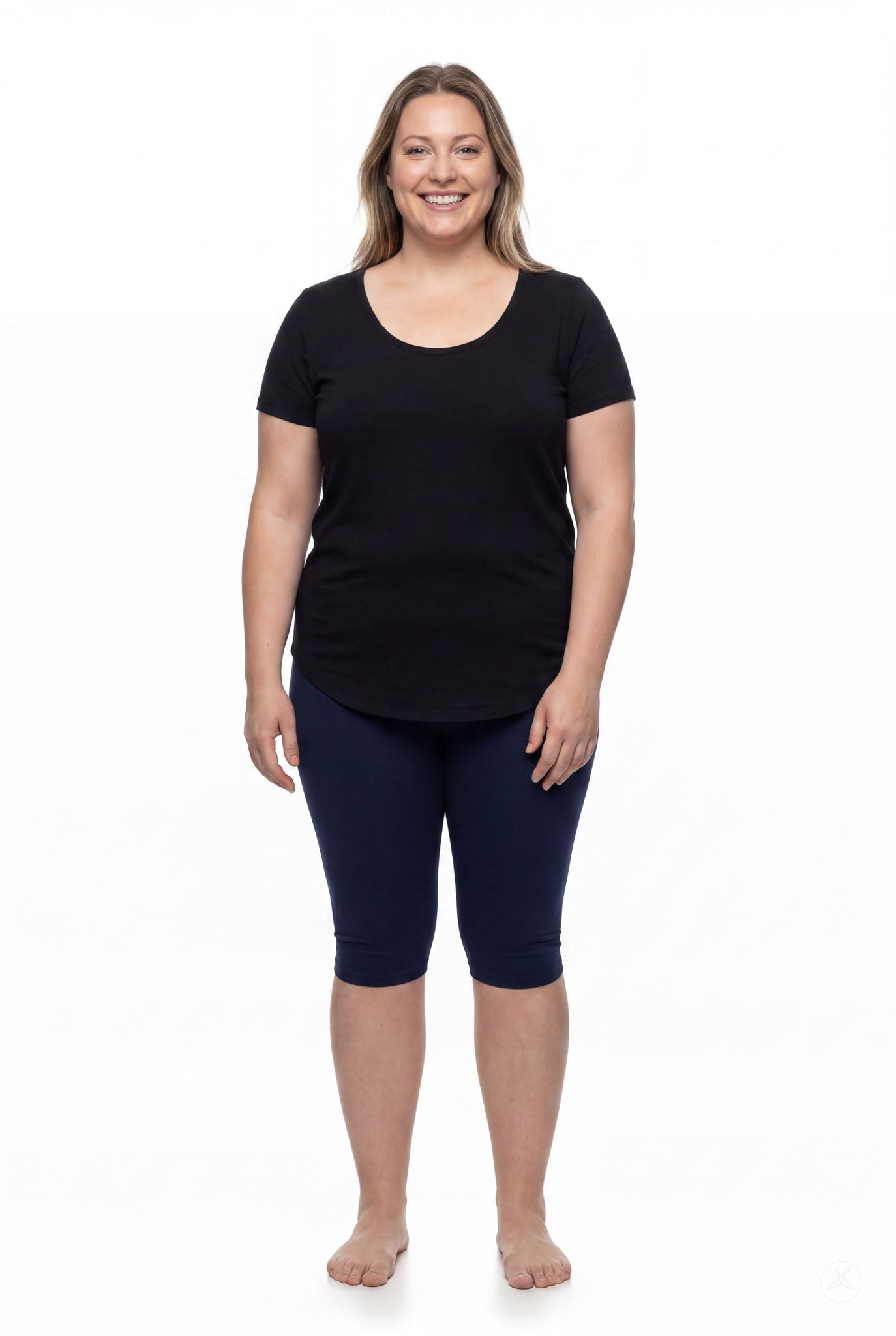 Smiling woman wearing SweetLegs Knee-Length Capri in navy blue paired with black short sleeve top barefoot on white background