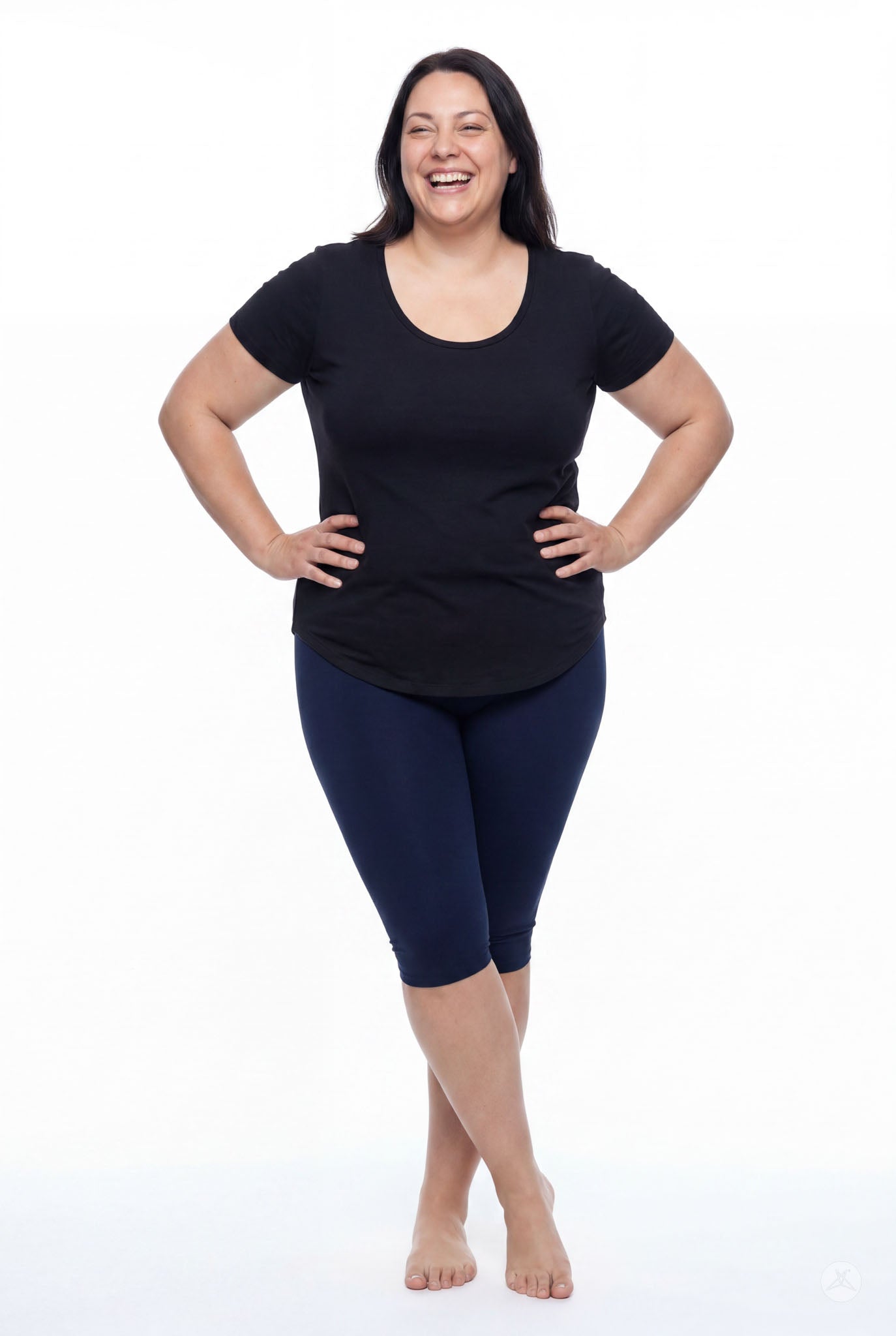 Smiling woman wearing SweetLegs Knee-Length Capri in navy blue paired with short sleeve black top barefoot on white background