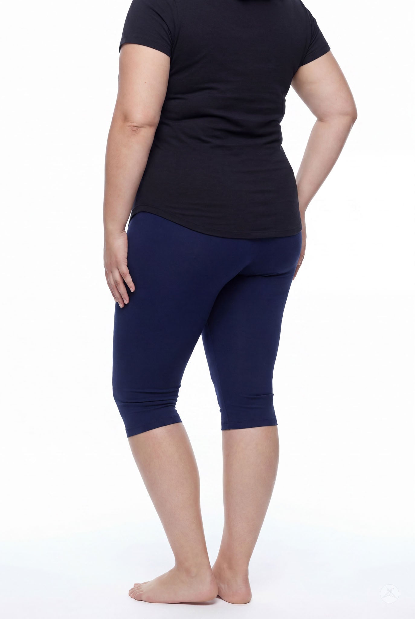 Plus size model shown from back wearing SweetLegs Knee-Length Capri in navy paired with black short sleeve top barefoot