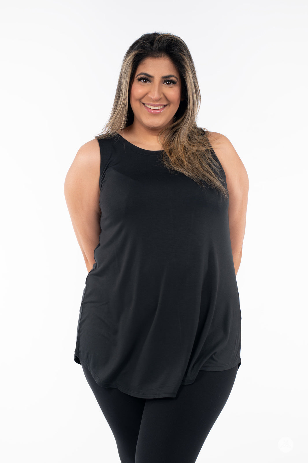 Plus-size model smiling wearing SweetTops High Neck Swing Tank in black paired with black leggings on white background