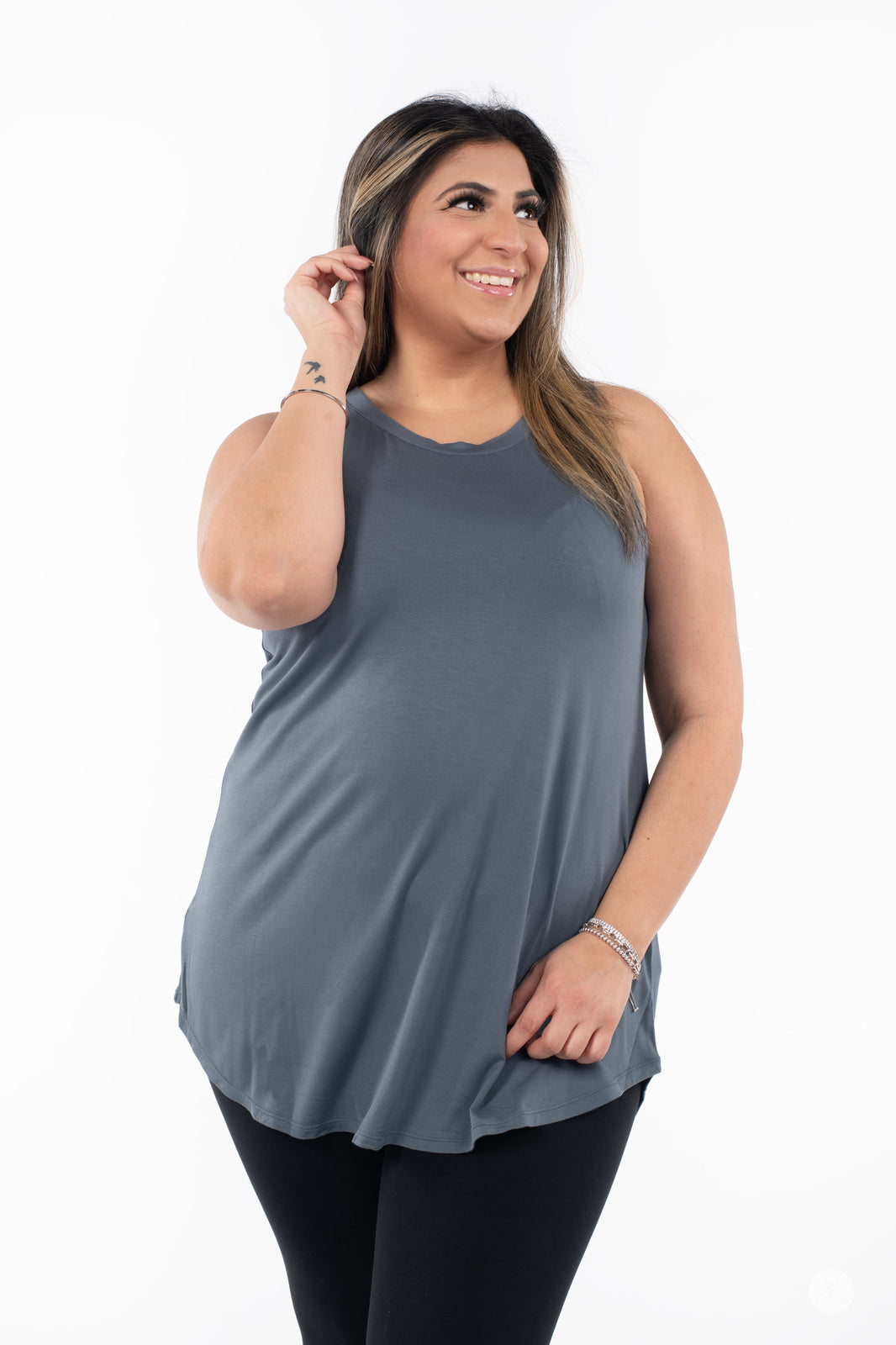 Plus-size model smiling while wearing SweetTops High Neck Swing Tank in slate paired with black leggings on white background