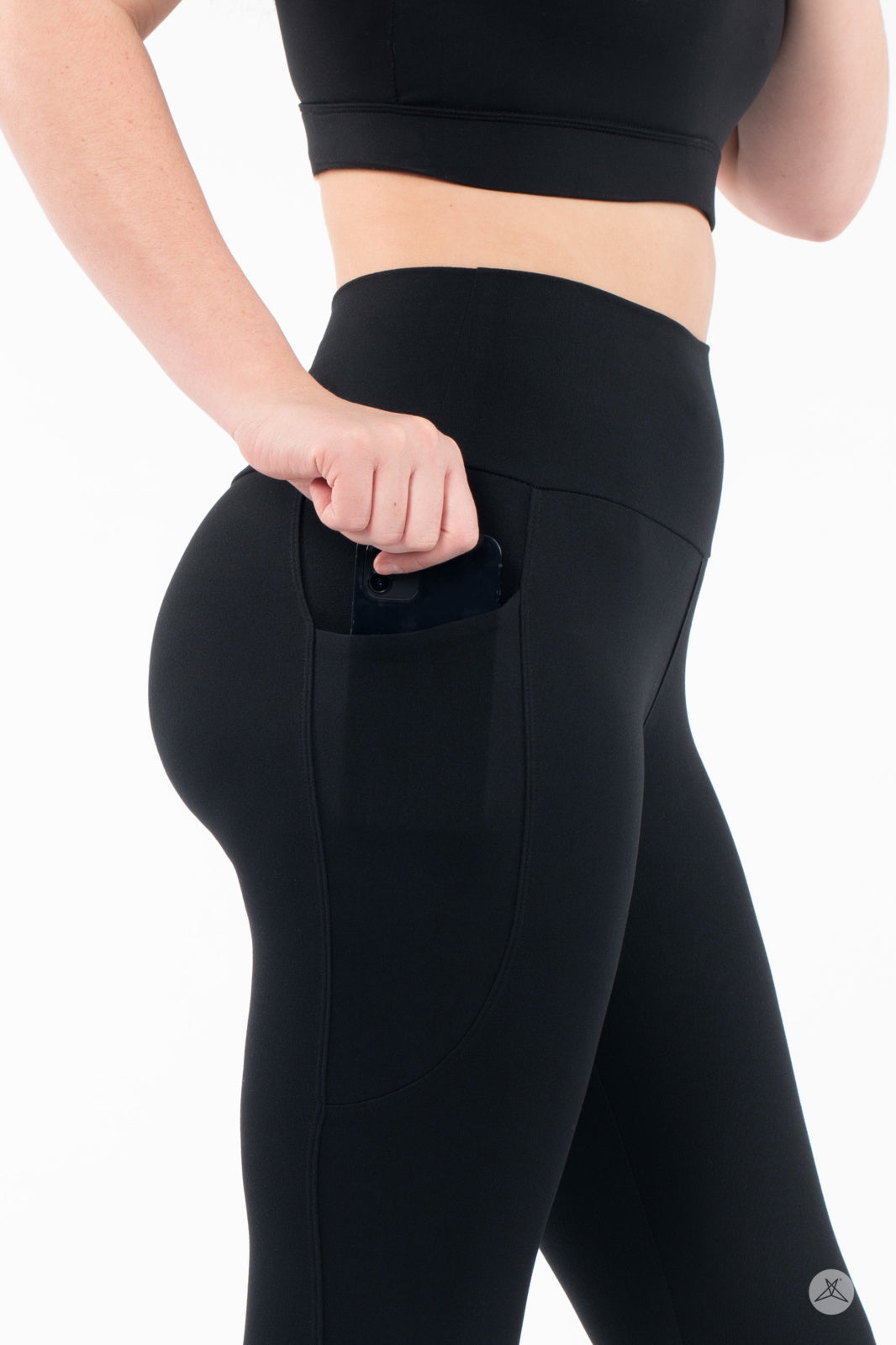 Woman sliding phone into side pocket of black SweetLegs High-Waist Pocket Crops with high-rise waistband