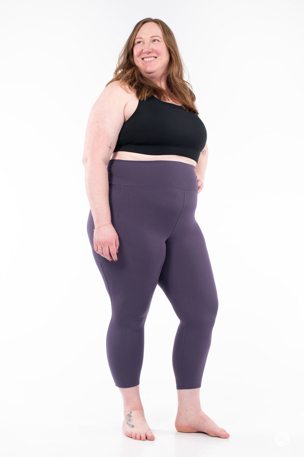 Plus-size model in plum SweetLegs High-Waist Pocket Crops smiling with hands relaxed at sides barefoot