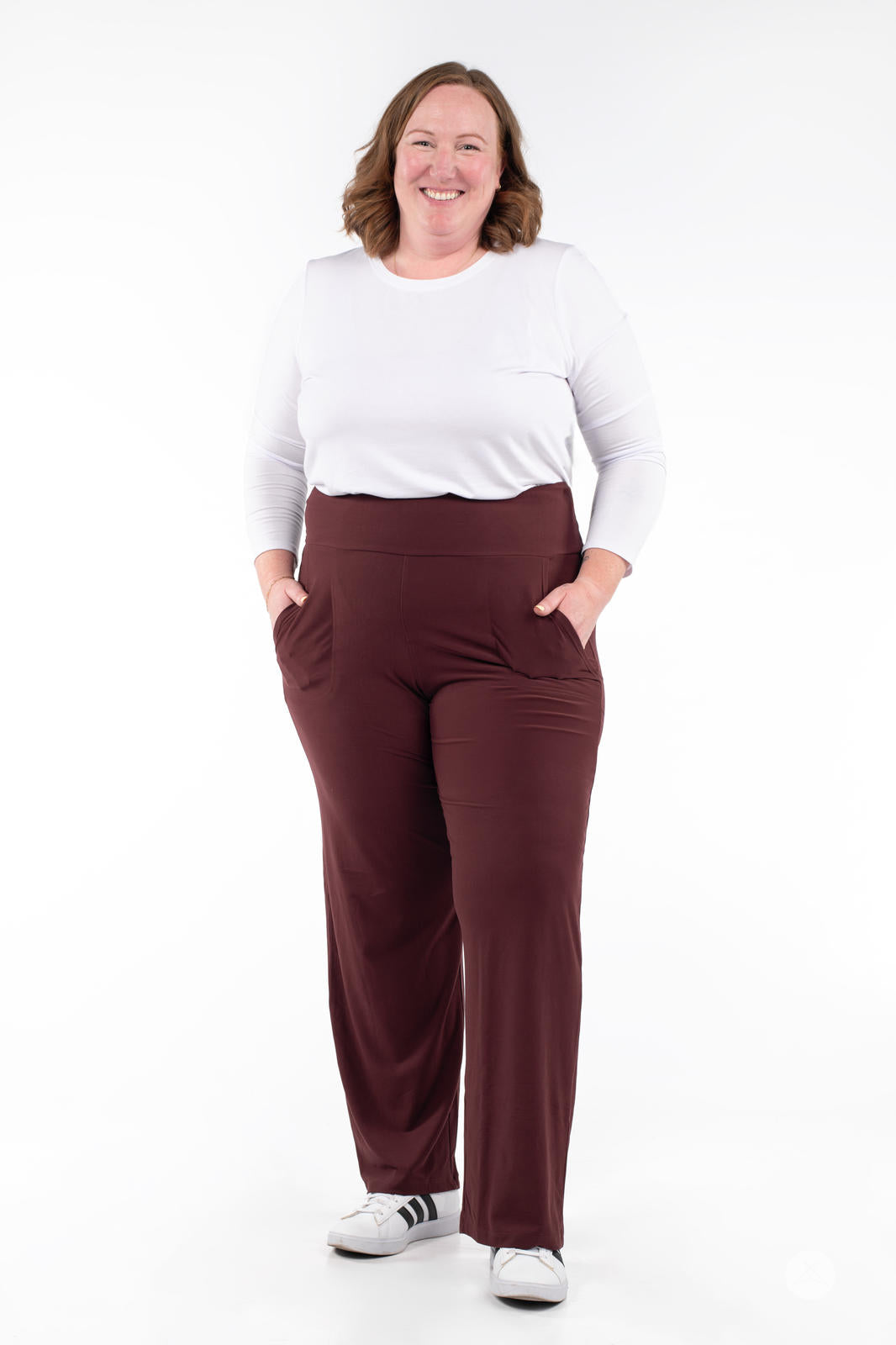 Smiling woman wearing SweetLegs High-Waist Wide Leg Pants in dark brown with hands in pockets and white sneakers