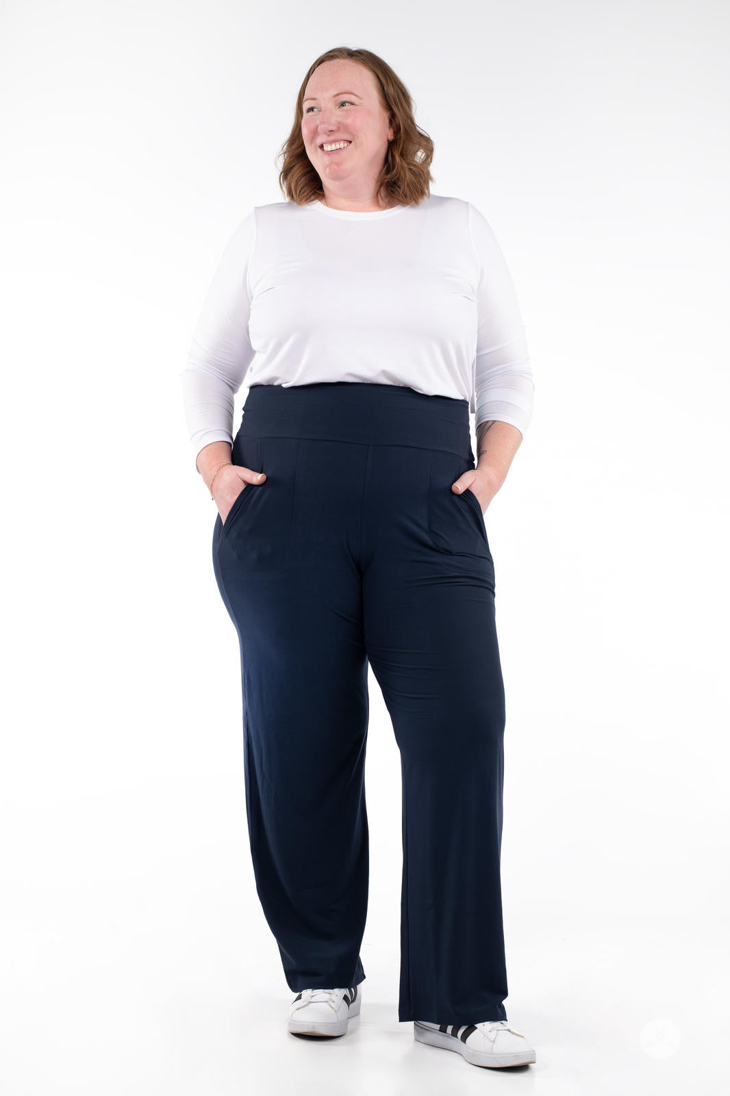 Smiling woman modeling SweetLegs High-Waist Wide Leg Pants in navy with hands in pockets and casual white sneakers