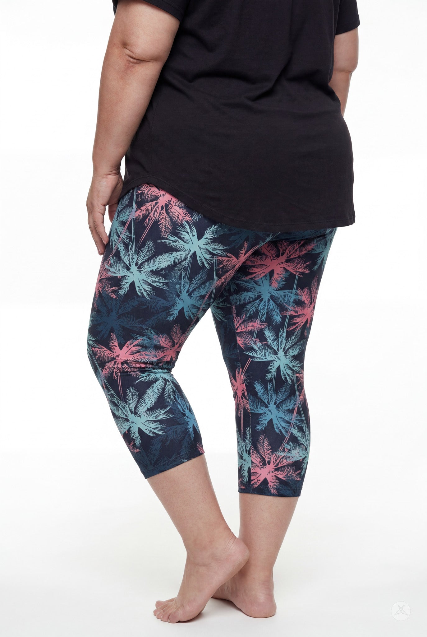 Rear view of woman wearing SweetLegs Tiki Nights Crops with coral and teal palm print and black top barefoot