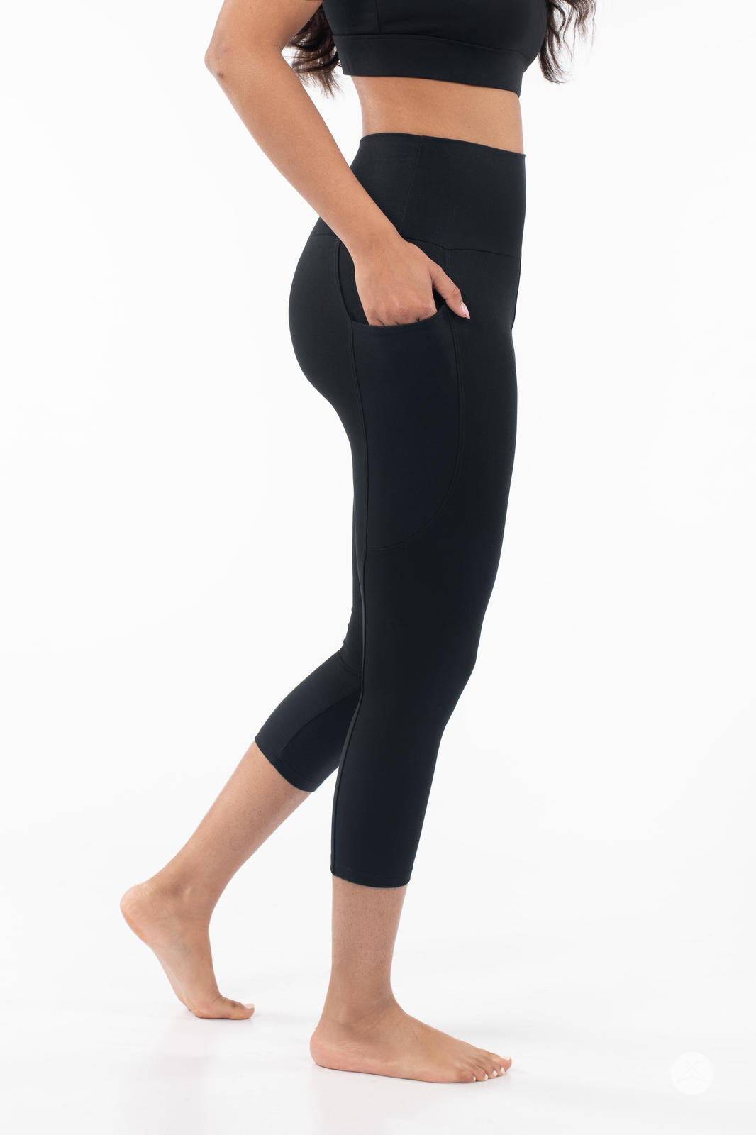 Side profile of woman wearing black SweetLegs High-Waist Pocket Crops with hand in side pocket on white background