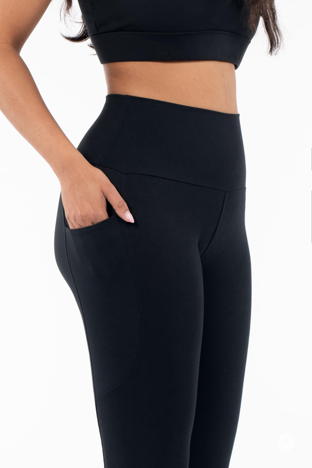 Close-up of woman wearing black SweetLegs High-Waist Pocket Crops with hand in side pocket on white background