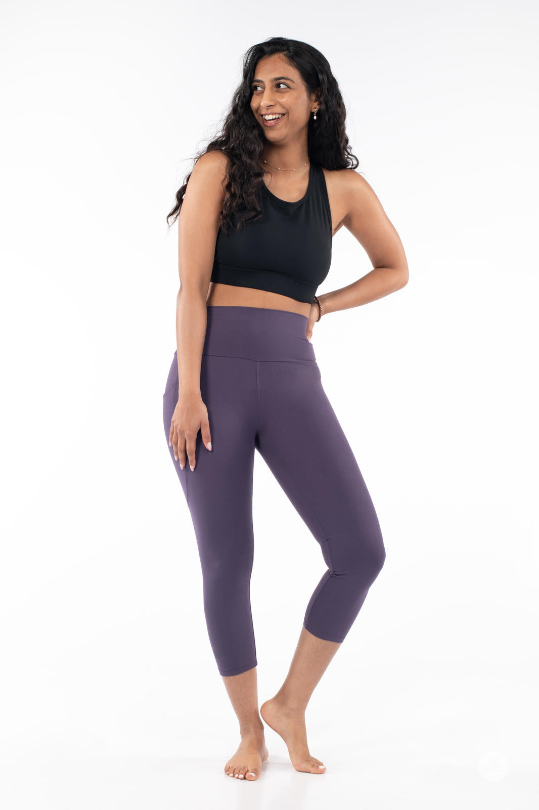 Woman standing barefoot wearing SweetLegs High-Waist Pocket Crops in plum with black sleeveless top on white background