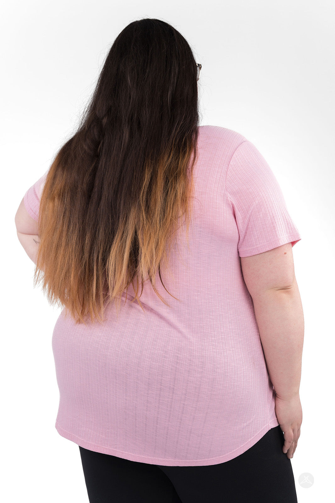 Back view of woman wearing soft rib-knit pink The Soft Ribbed Tee by SweetLegs Canada with curved hem and short sleeves