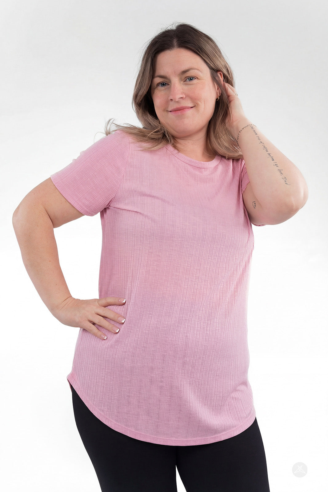 Plus-size model wearing pink The Soft Ribbed Tee by SweetLegs Canada with short sleeves and curved hem front view