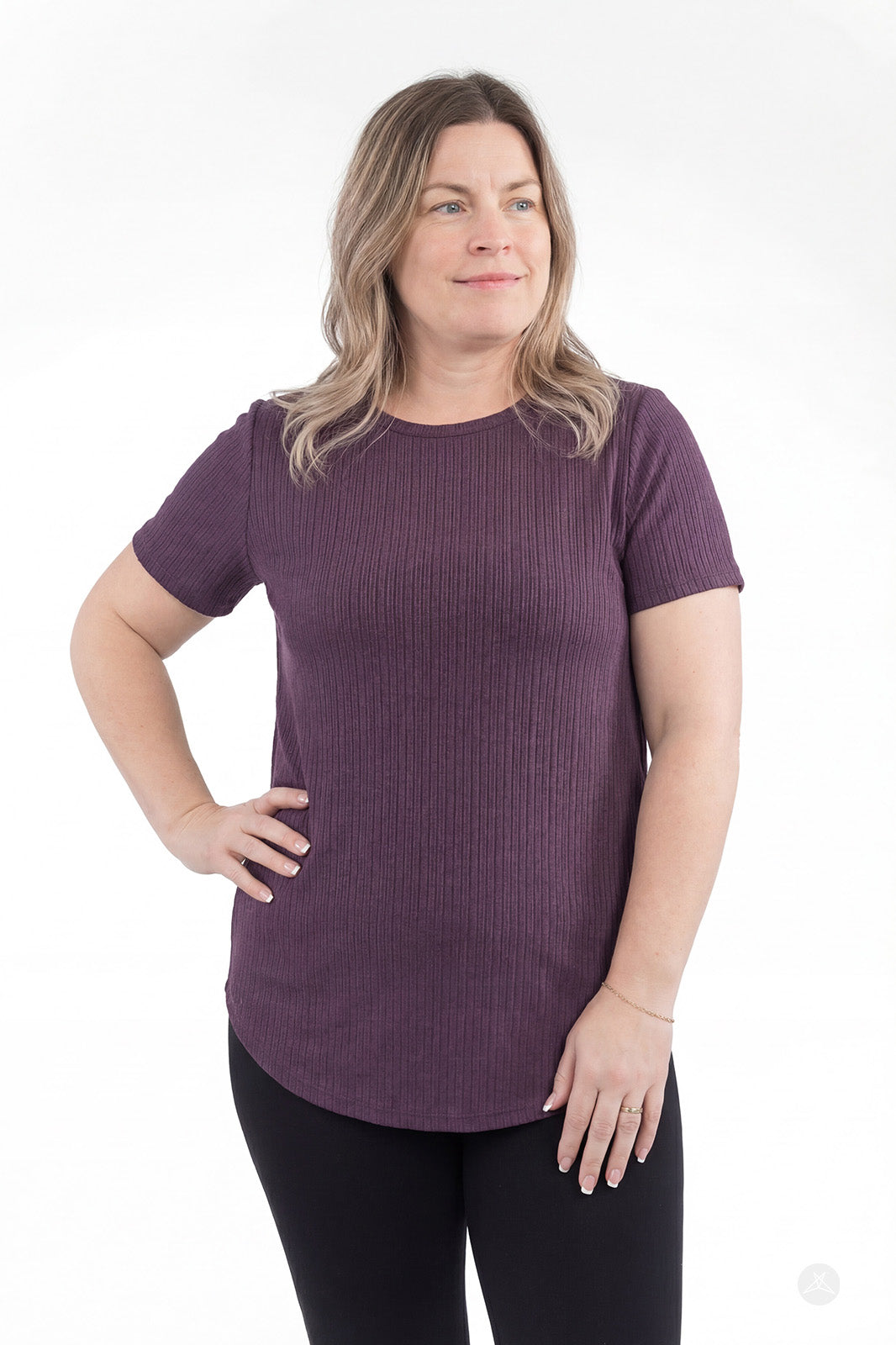 Woman wearing purple The Soft Ribbed Tee by SweetLegs Canada with curved hem and crew neck, standing with hand on hip
