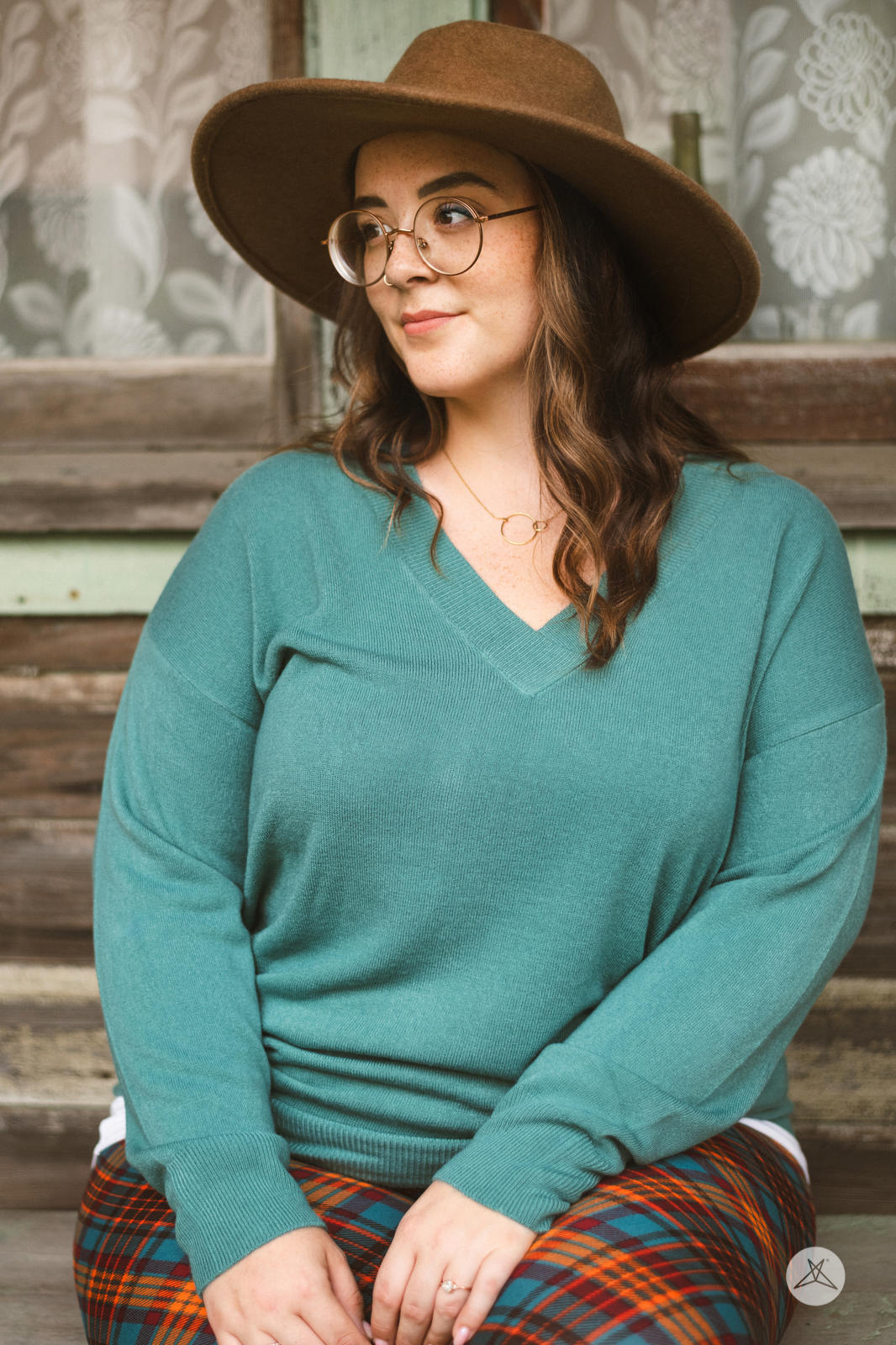 Woman wearing SweetTops Soft Knit V-Neck Sweater in dusty teal with relaxed fit and ribbed cuffs seated outdoors