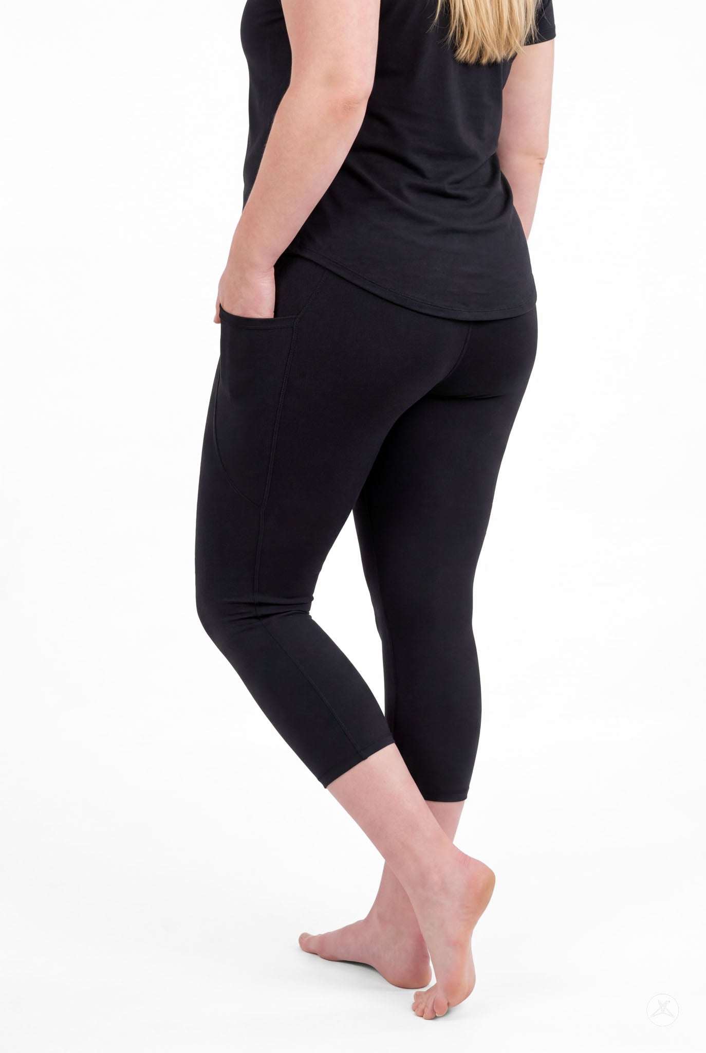 Woman standing barefoot showing back view wearing SweetLegs Black Pocket Crops with pockets and black top