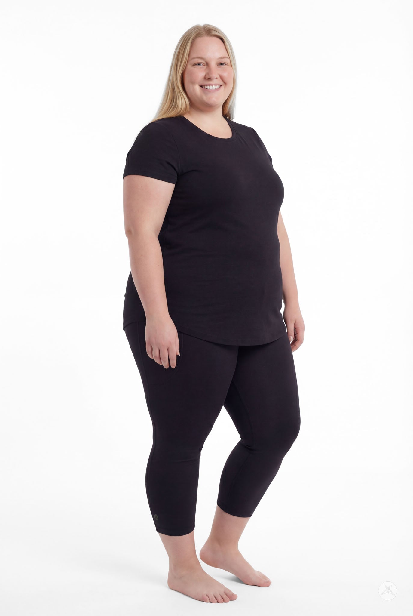 Plus size woman wearing SweetLegs Black Pocket Crops and black short sleeve top standing barefoot smiling