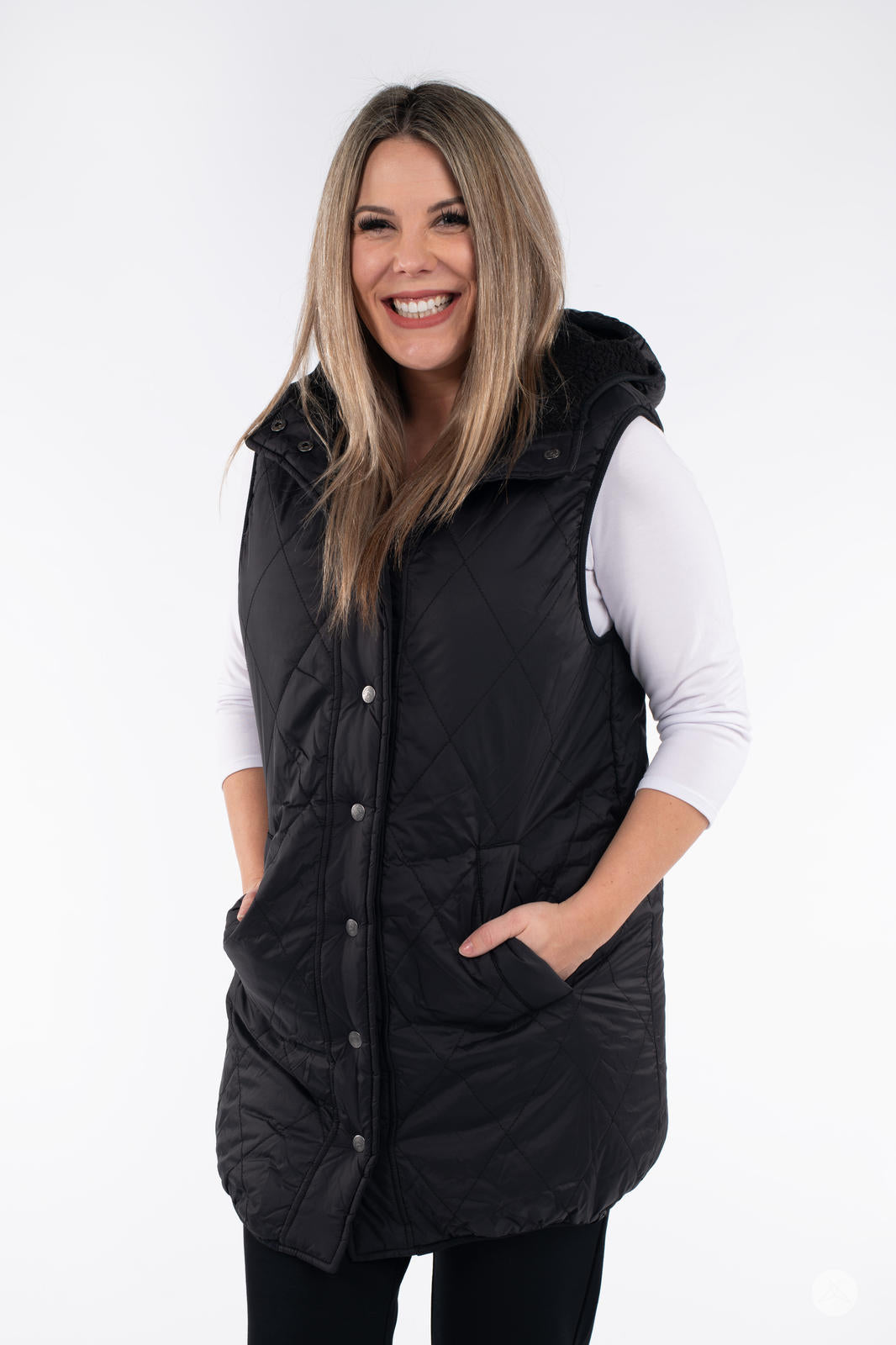 Smiling woman wearing SweetLegs Canada Reversible Quilted Sherpa Vest in black with hands in pockets