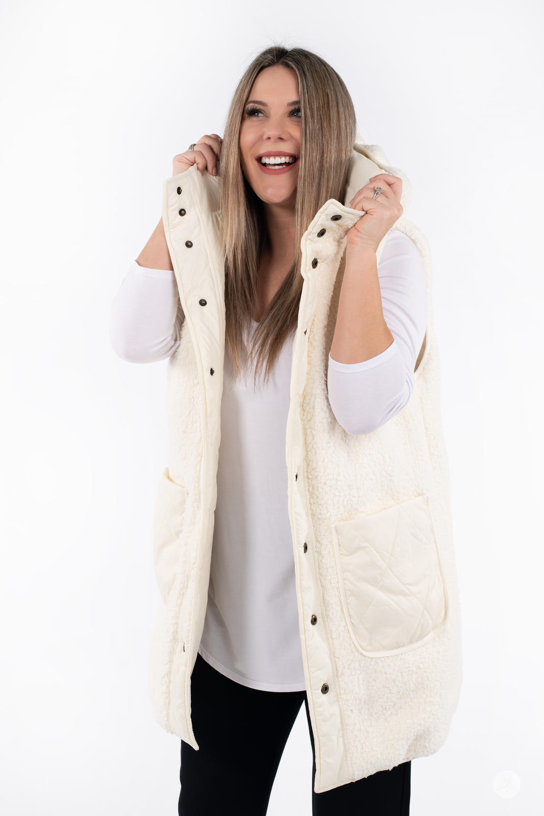 Woman smiling while wearing cream SweetLegs Canada Reversible Quilted Sherpa Vest with hood and quilted pocket visible