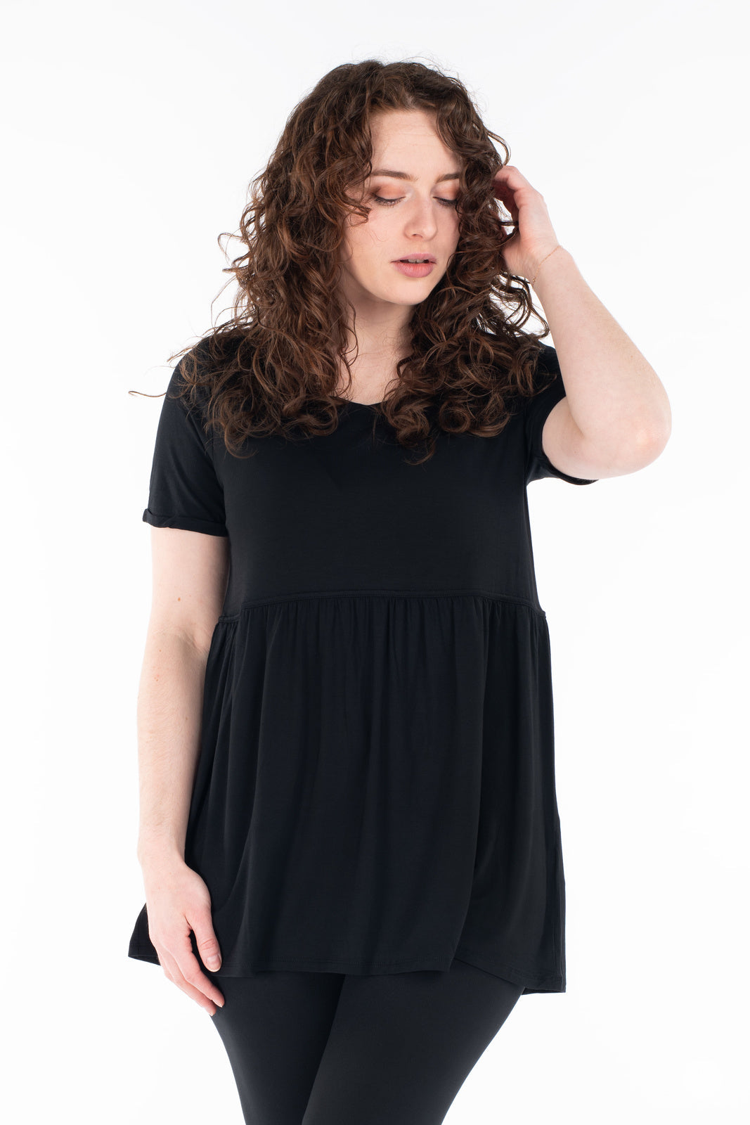 Woman wearing black Babydoll Tee by SweetLegs Canada with short sleeves and relaxed babydoll fit looking down